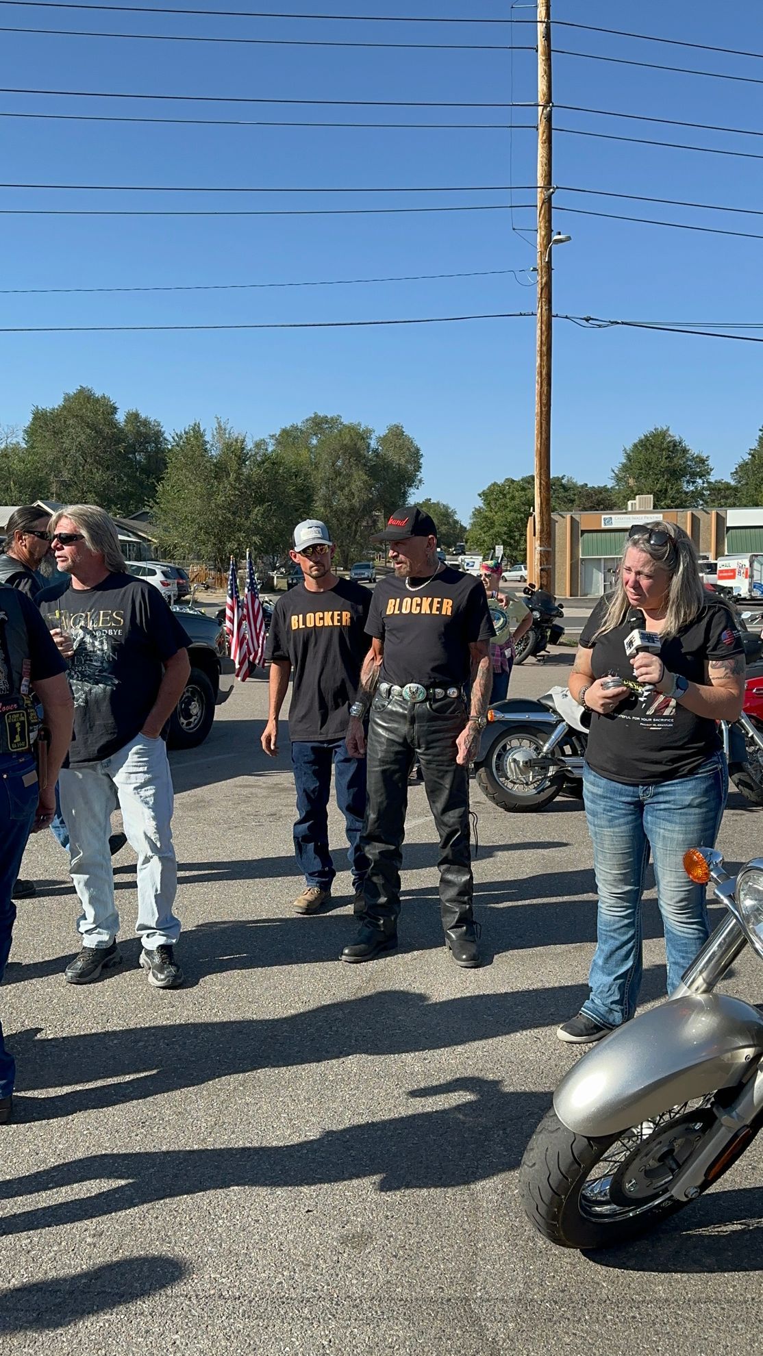 A group of people standing next to a motorcycle in a parking lot.