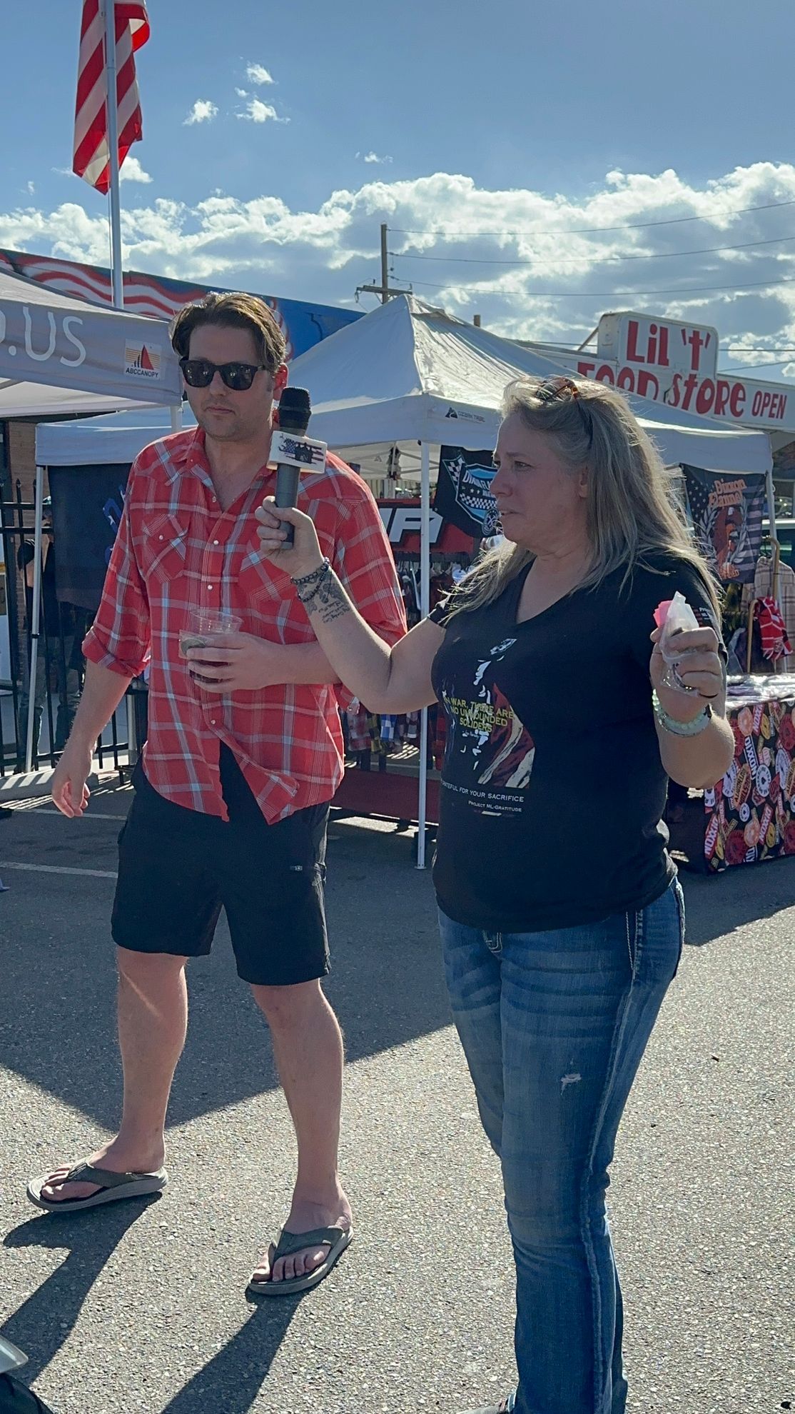 A man and a woman are standing next to each other on a street . the woman is holding an ice cream cone.