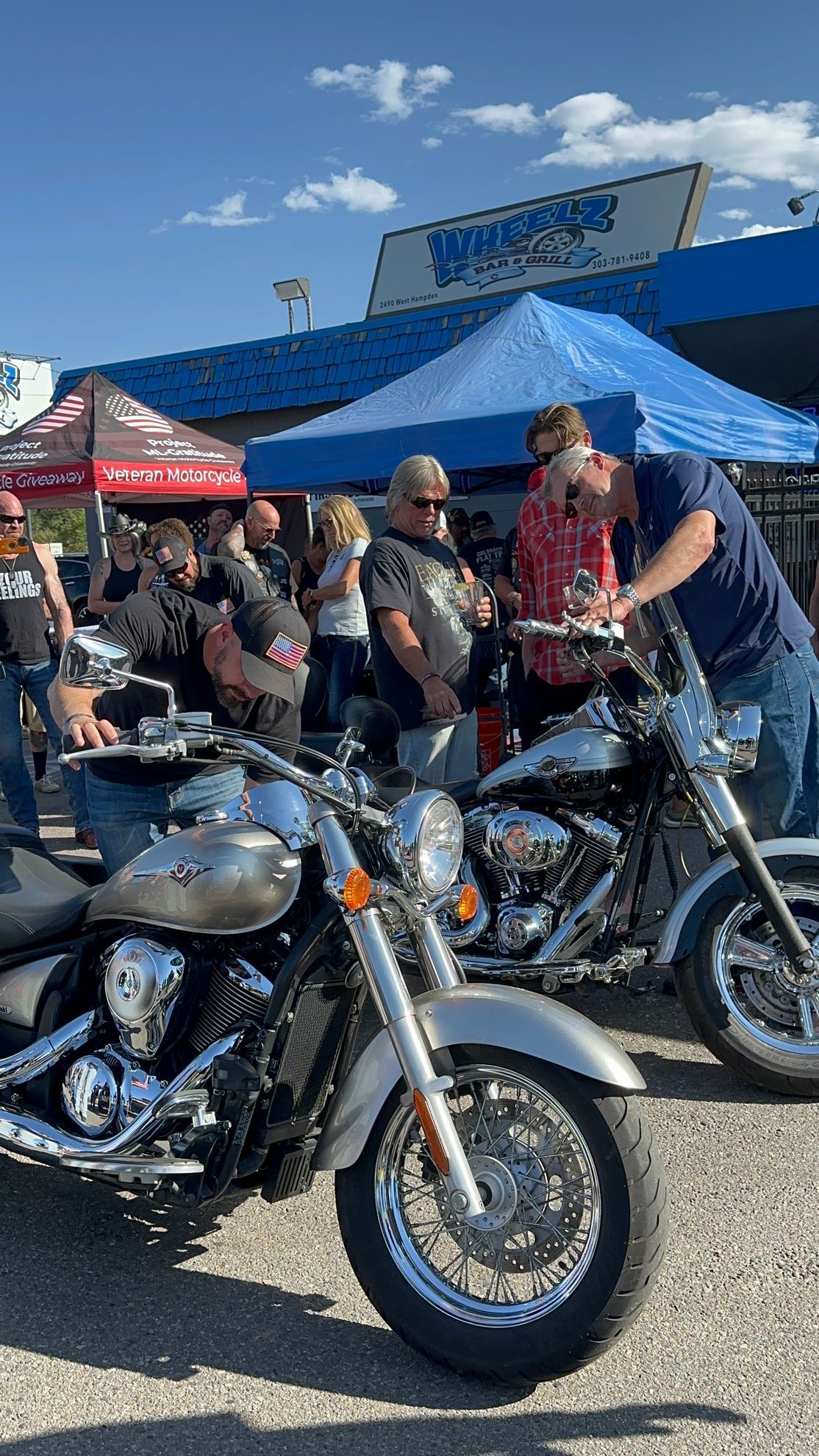 A group of people are standing around motorcycles in front of a building.