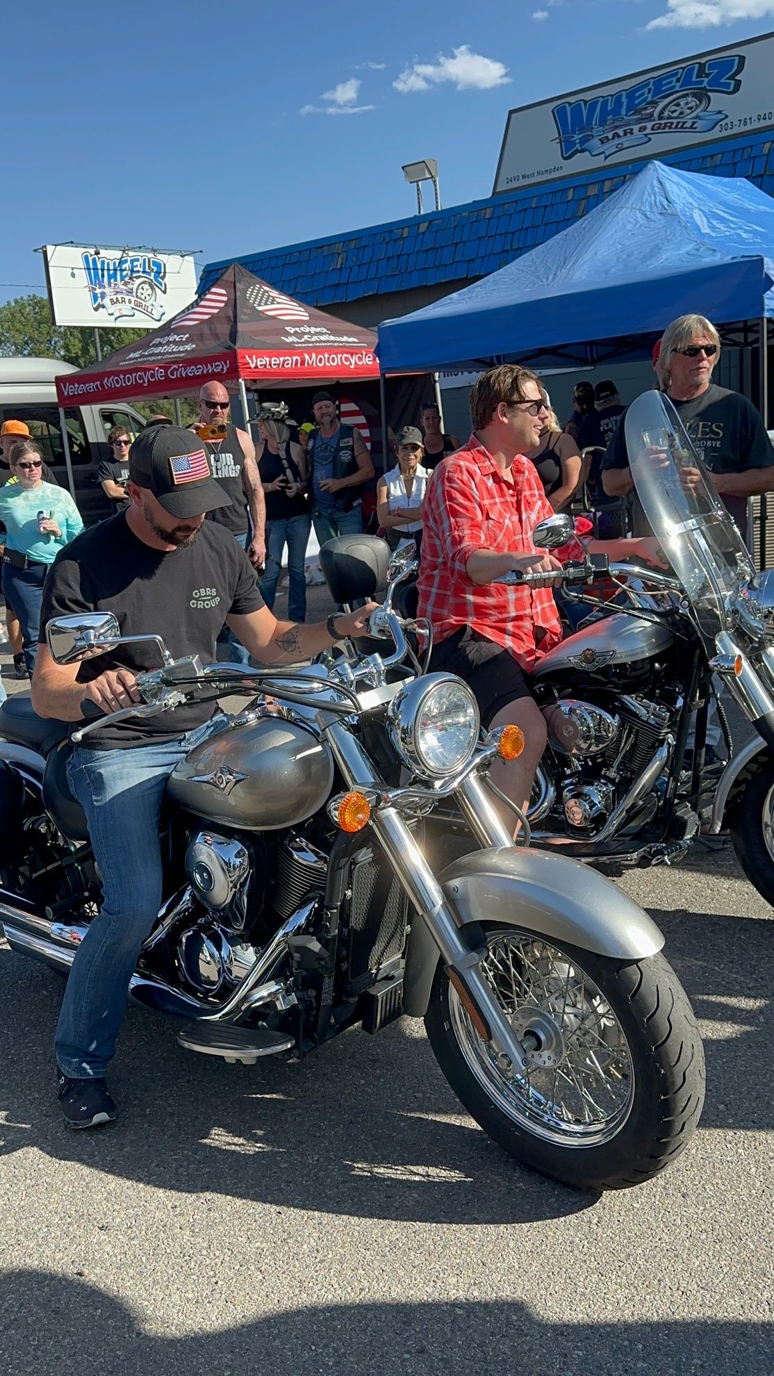 A group of people are sitting on motorcycles in front of a building.