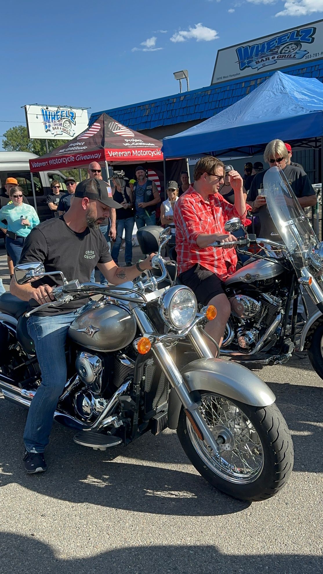 A group of people are sitting on motorcycles in front of a building.