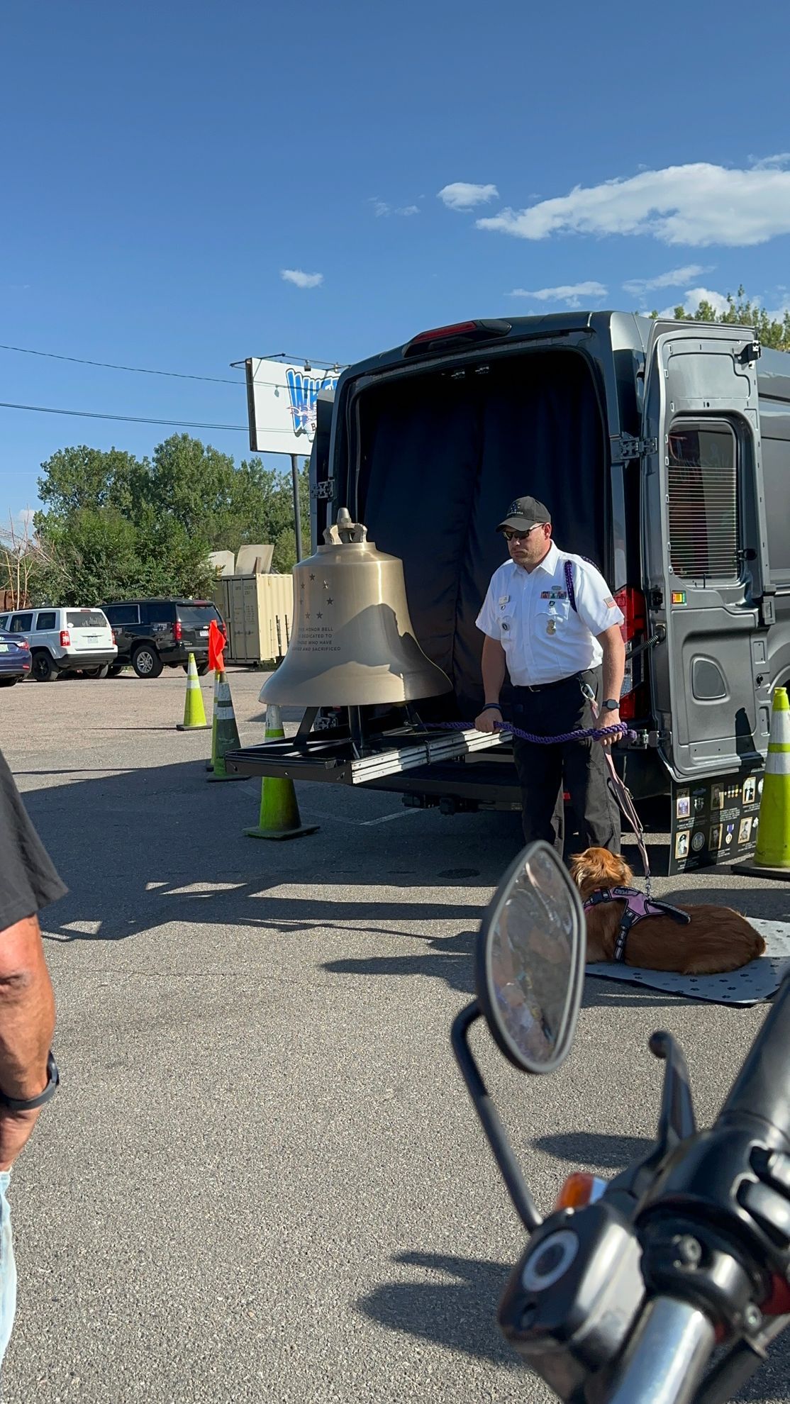 A man is loading a large bell into the back of a van.