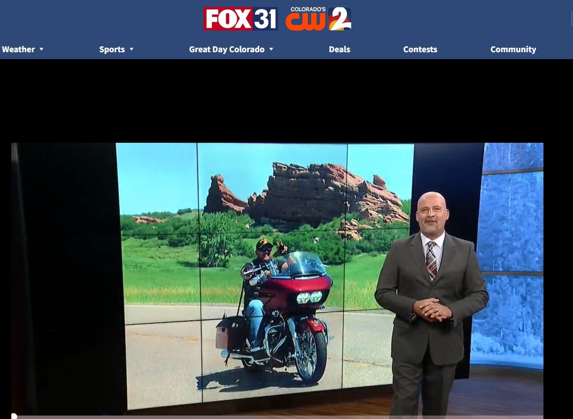 A man in a suit and tie is standing in front of a screen that says fox 31