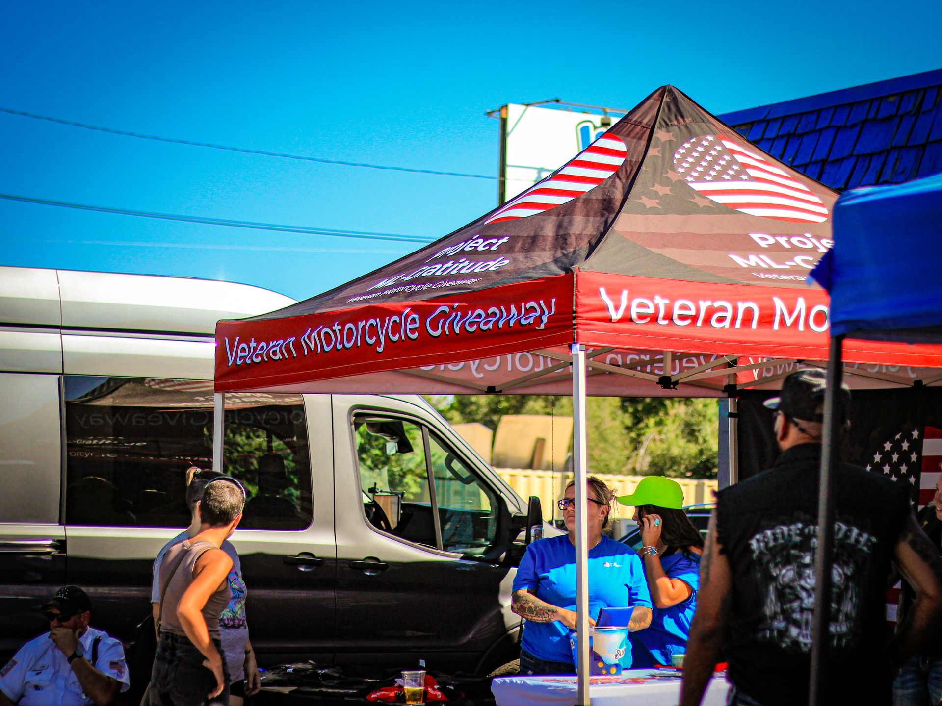 A group of people standing under a tent that says veteran mc