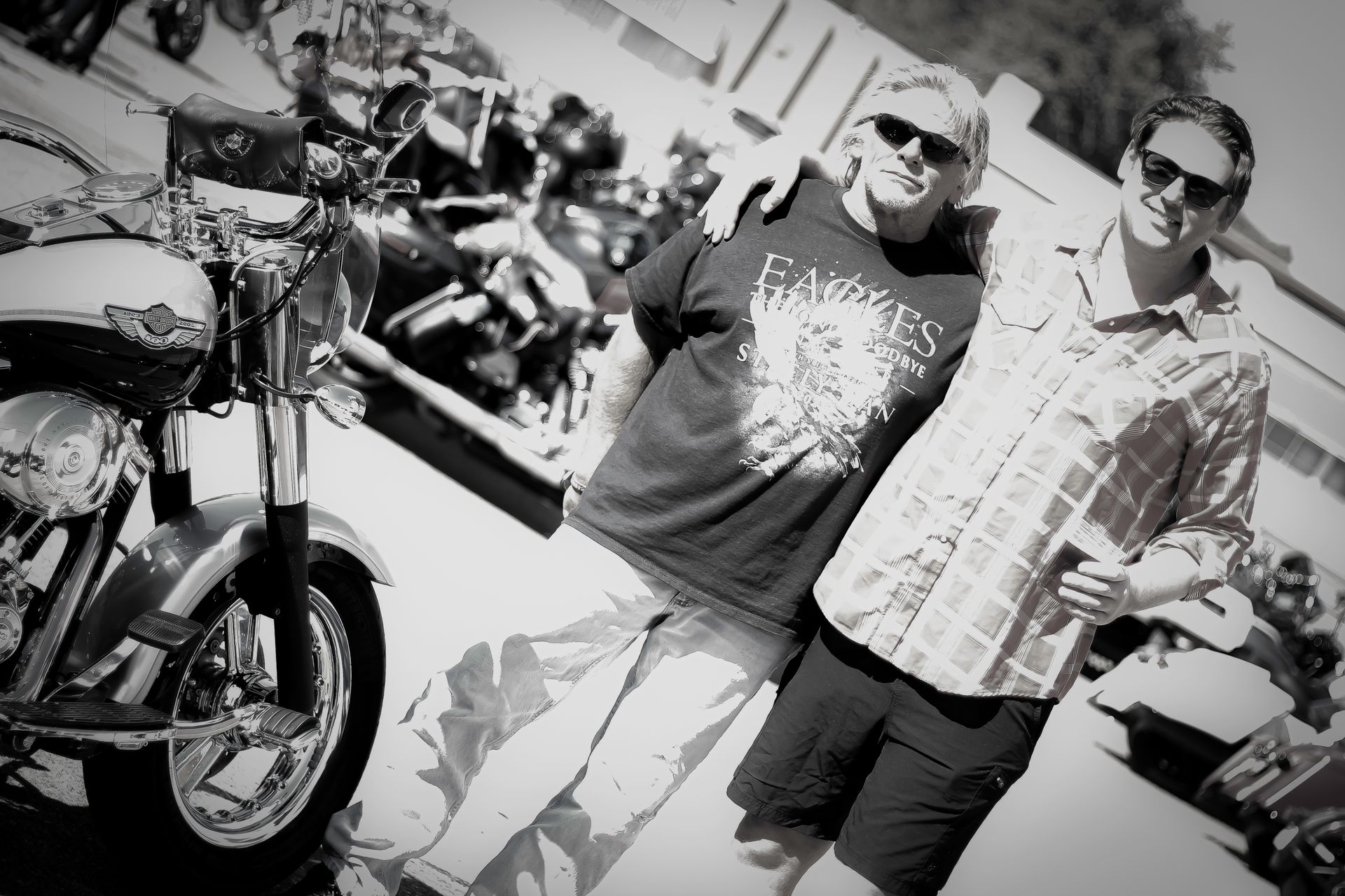 Two men are posing for a picture in front of a motorcycle
