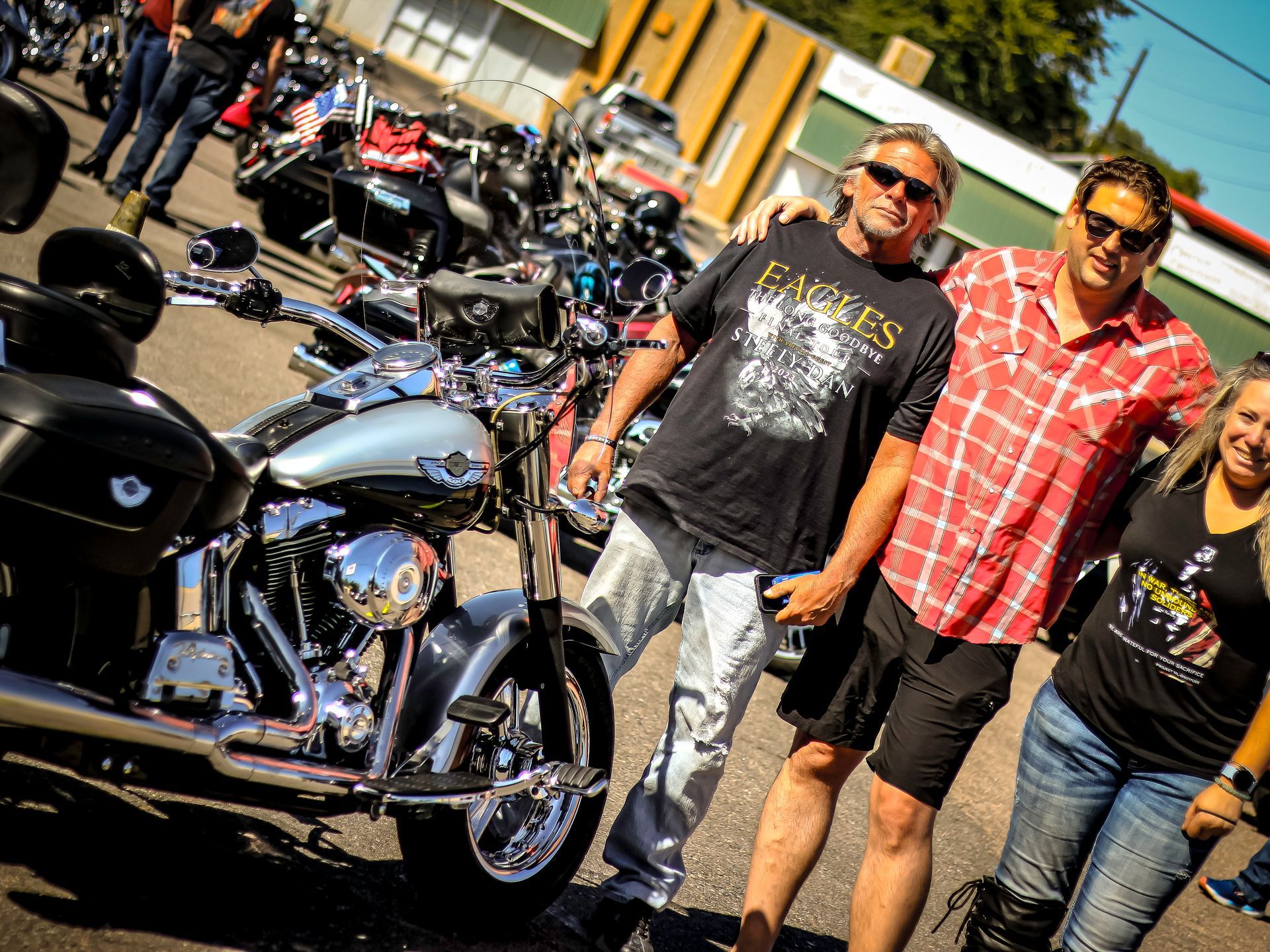 A group of people are posing for a picture in front of a harley davidson motorcycle.