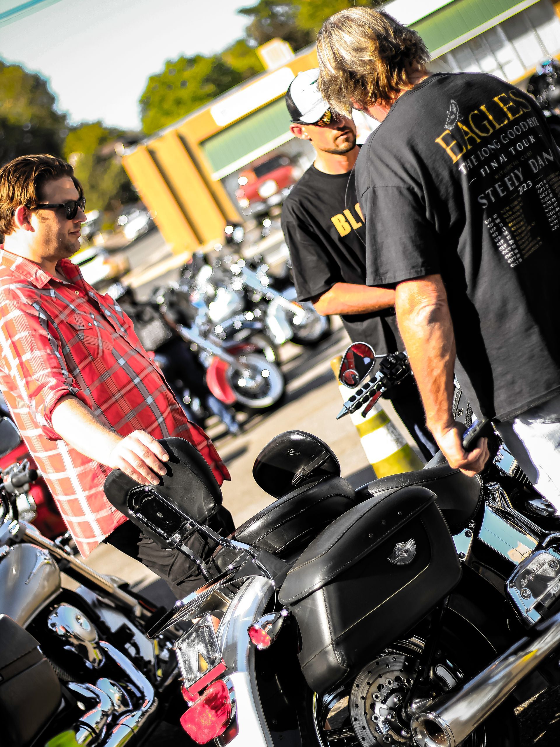 A man wearing an eagle shirt is standing next to a motorcycle