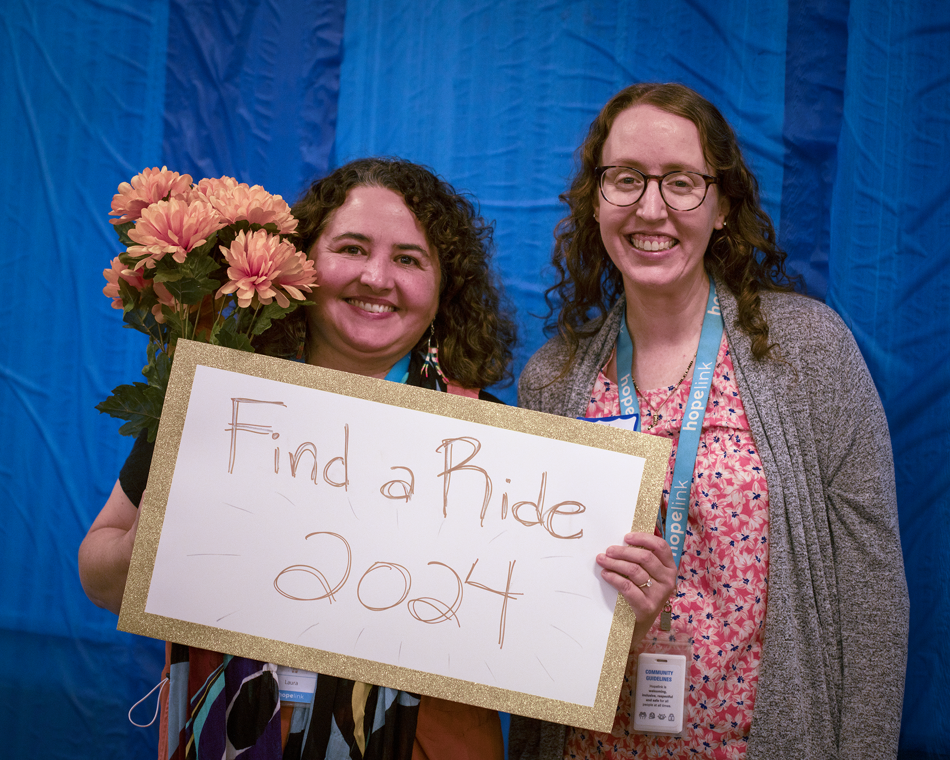 Two people holding a sign with a blue background