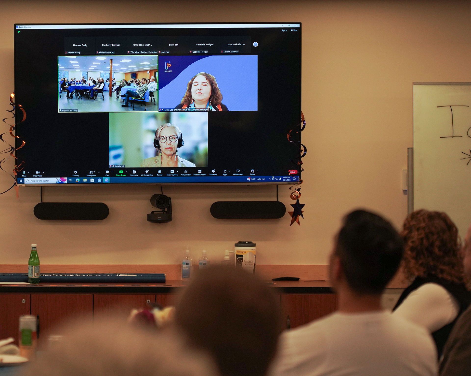 People in room watch attendees on screen
