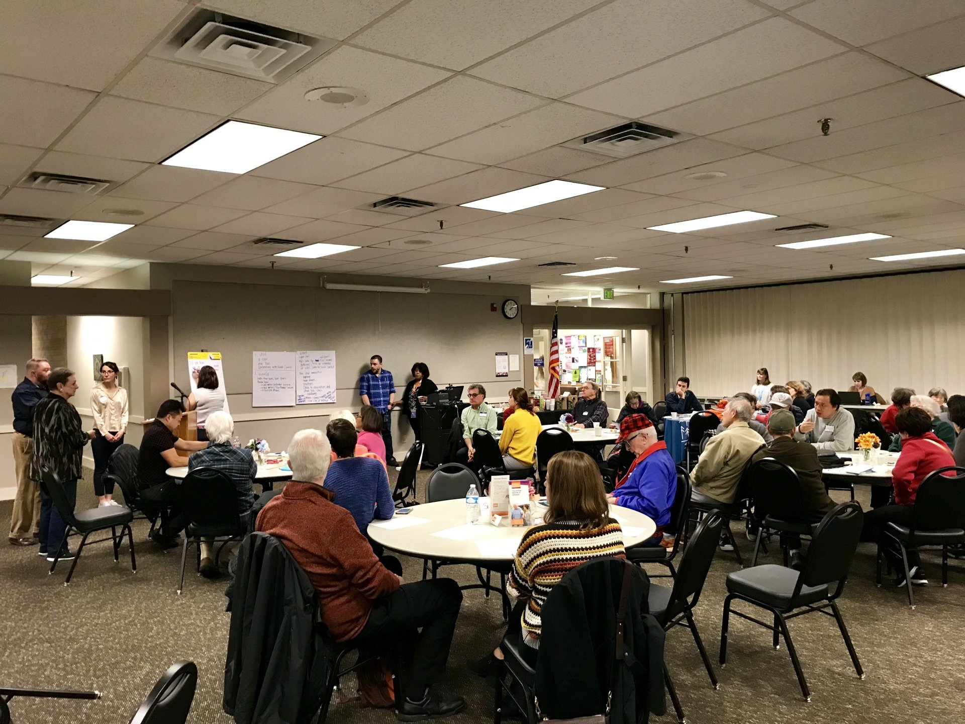 A room full of people sitting at tables having a discussion