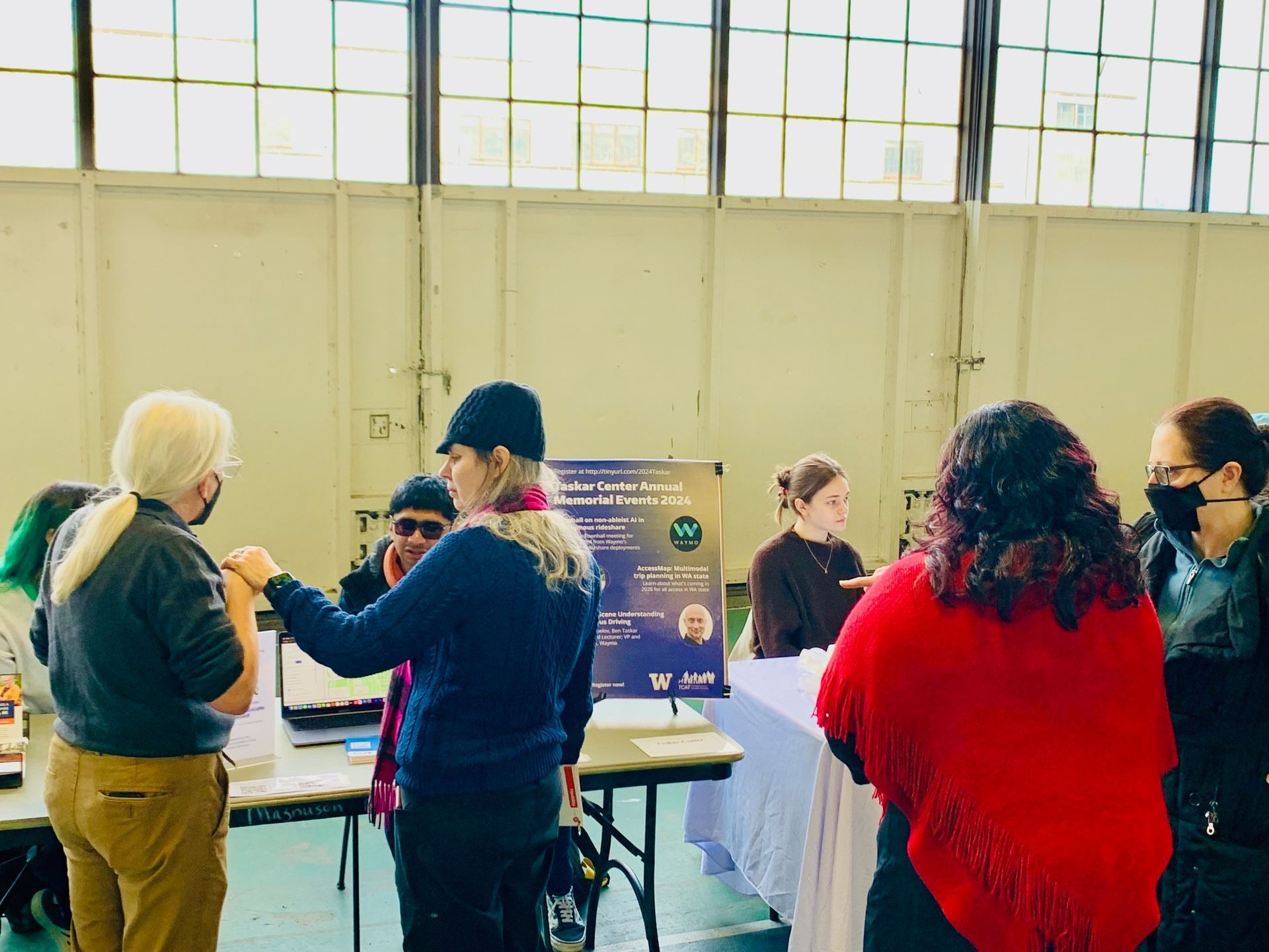 Many people with a variety of disabilities standing by the AccessMap TCAT table.