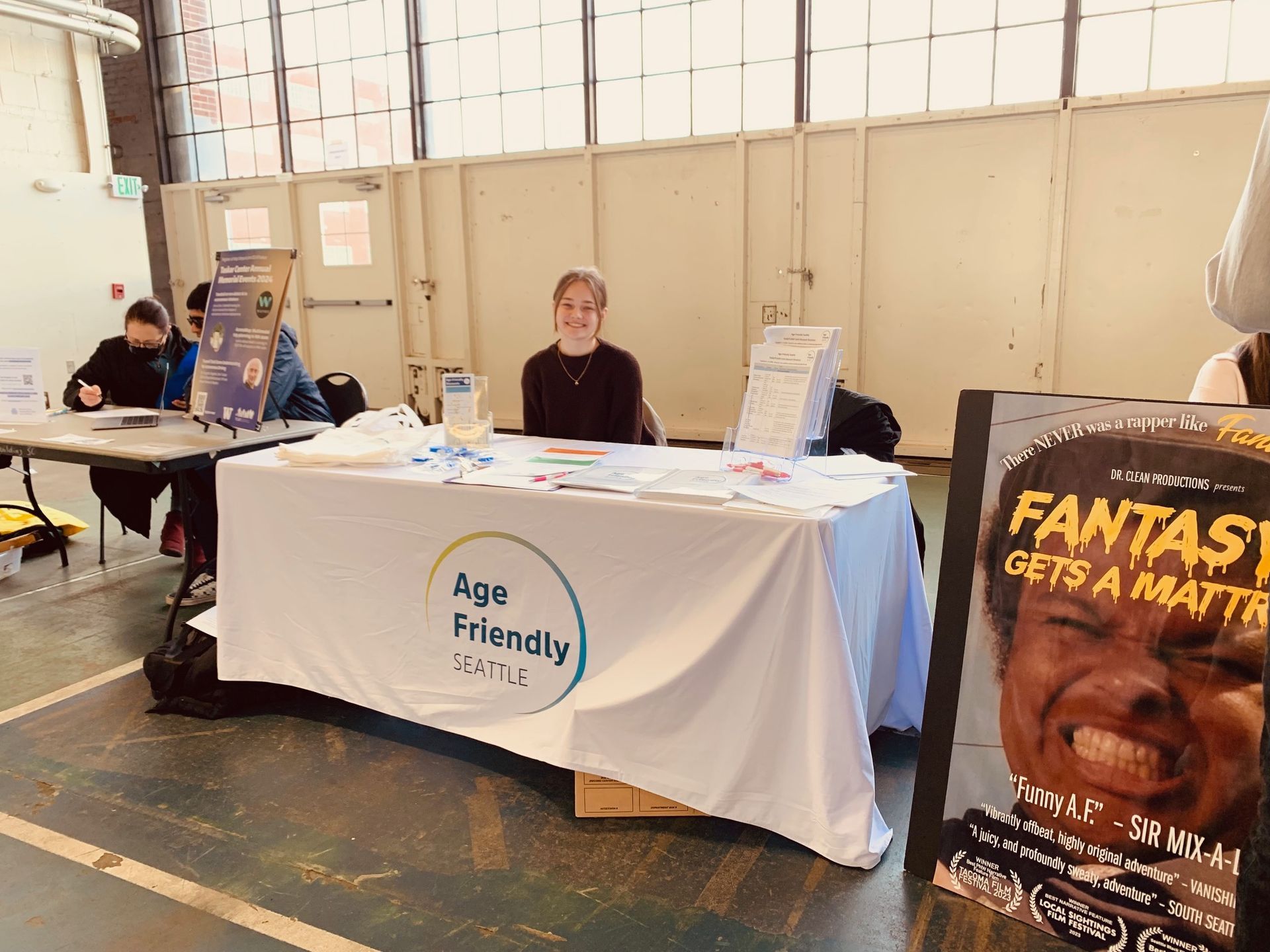 Age Friendly Seattle staff sitting at their table next to a Fantasy A Film Poster at the next table.