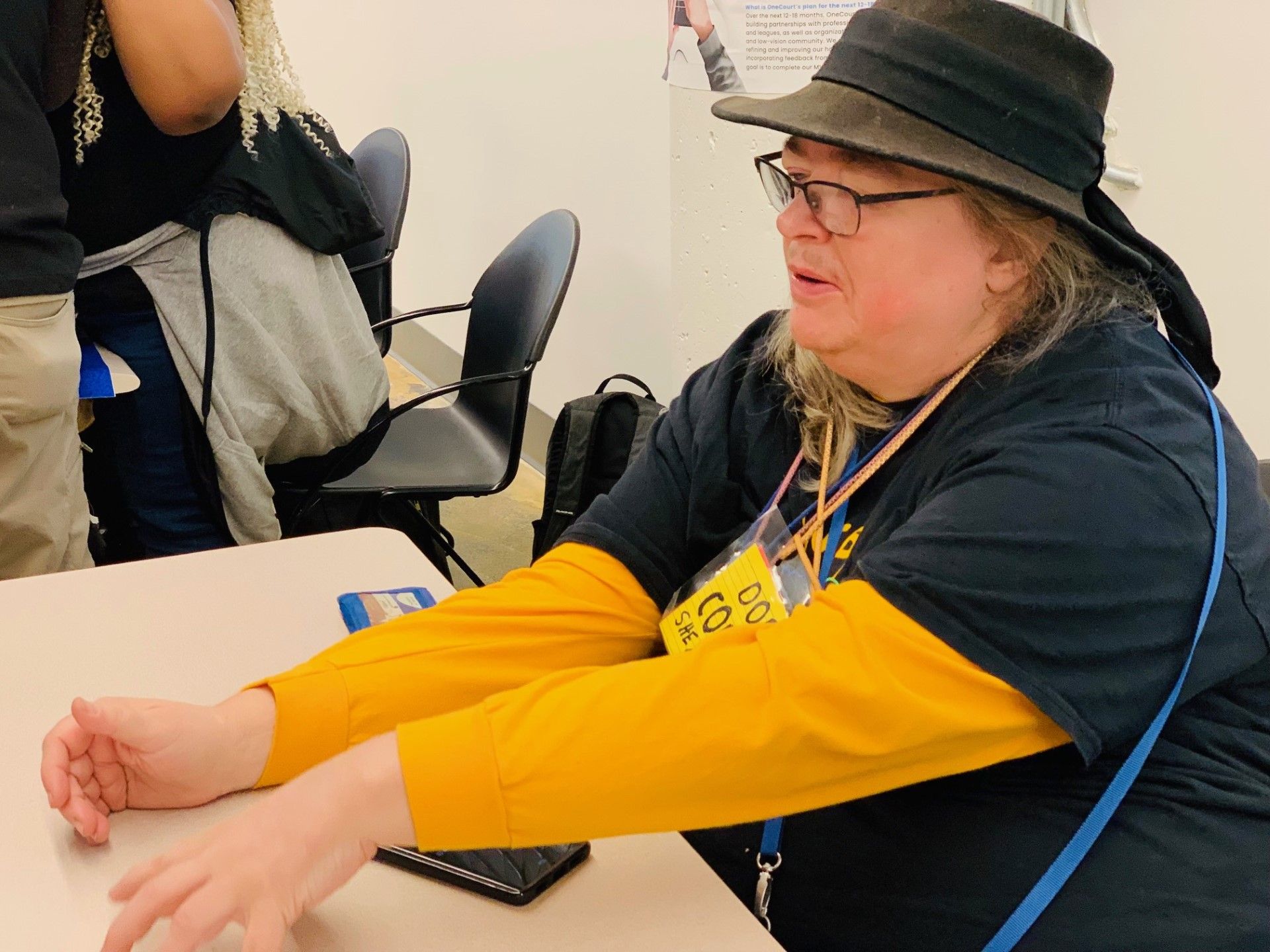 Dorene Cornwell wearing a brown hat and a black and yellow shirt, explaining Find a Ride to attendees.