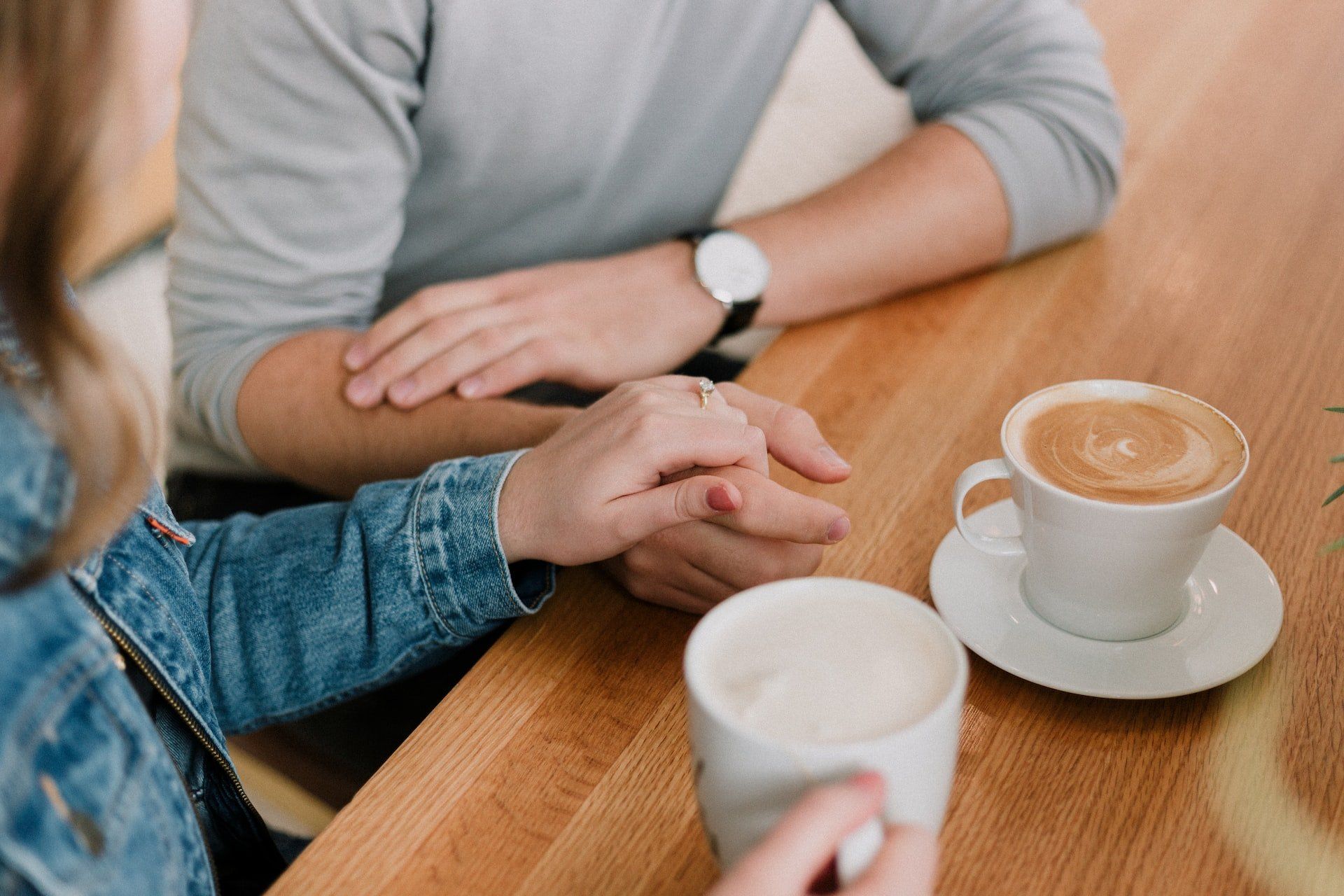 twee vrouwen die koffie drinken en elkaars steunen door hand vast te houden