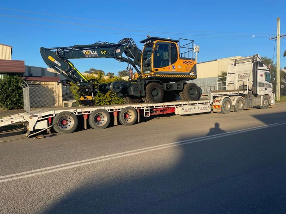 A Truck Is Carrying A Large Excavator On A Flatbed Trailer — Armour Transport Logistics In Mackay, QLD