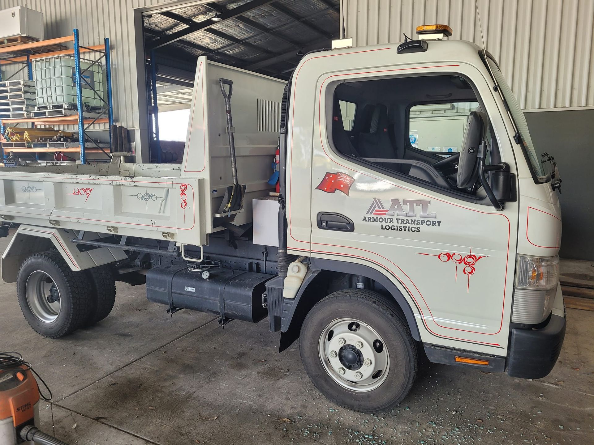 A Small Tipper Truck Parked Inside Garage — Armour Transport Logistics In Rutherford, NSW