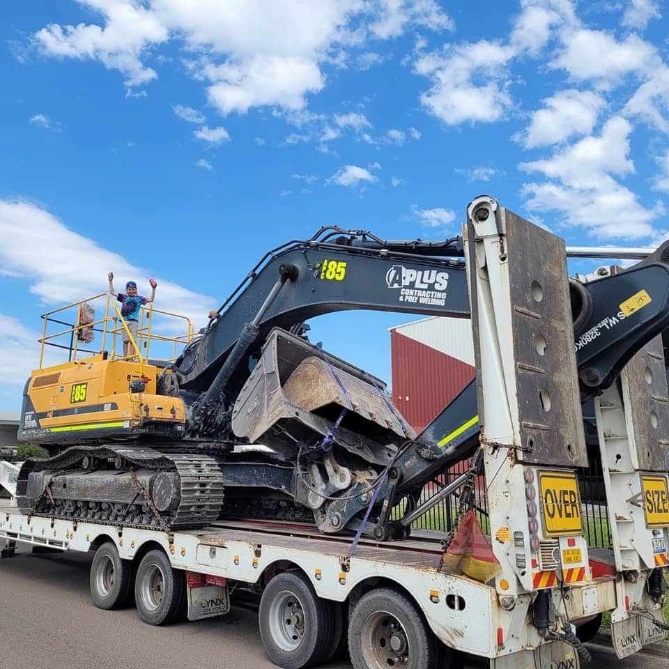 A Yellow Excavator Is On The Back Of A White Truck — Armour Transport Logistics In Sydney, NSW