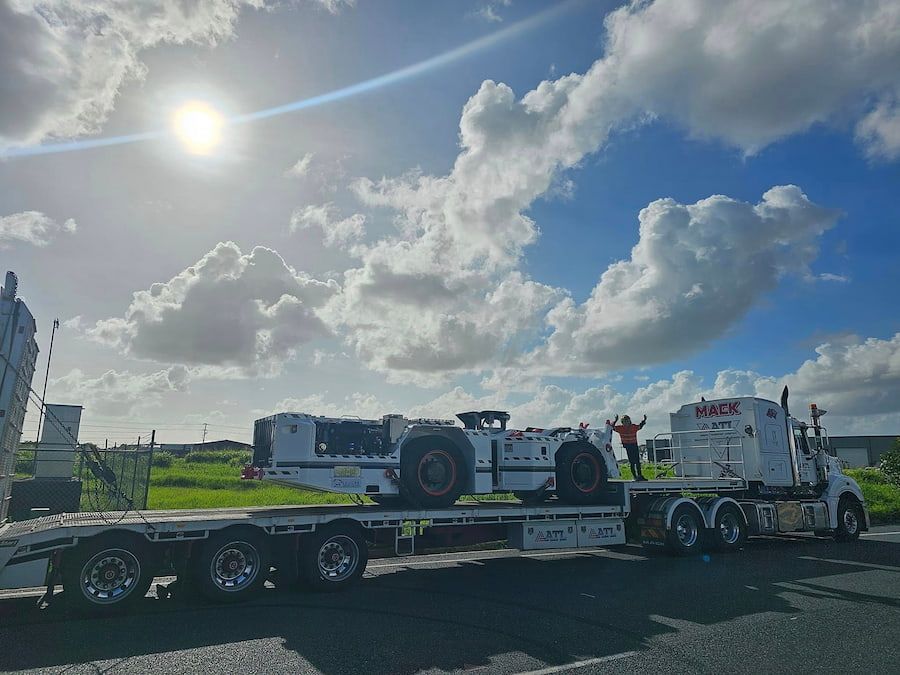 A Semi Truck Is Carrying A Large Vehicle On A Flatbed Trailer — Armour Transport Logistics In Singleton, NSW