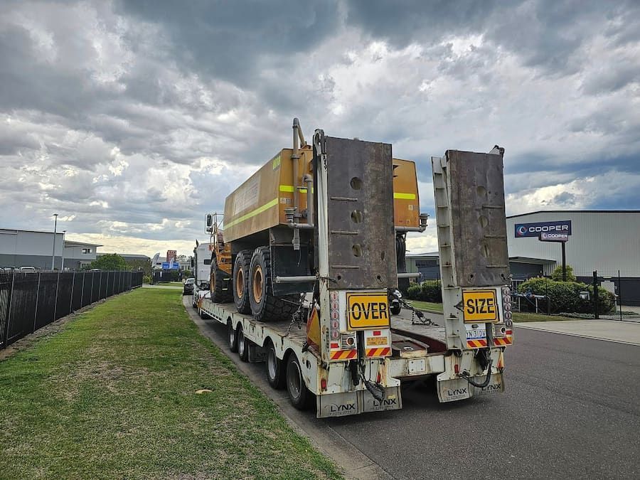 A Semi Truck With A Dump Truck On The Back Is Driving Down A Street — Armour Transport Logistics In Melbourne, VIC