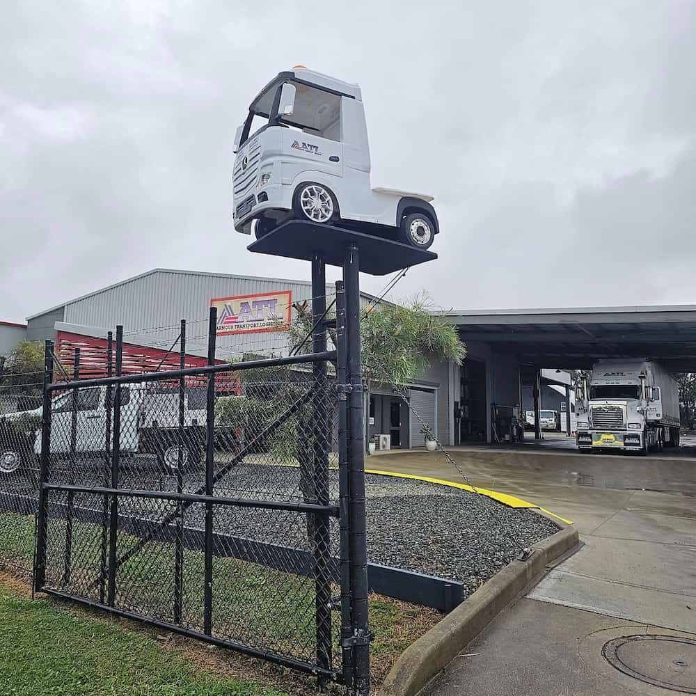 A Model Truck Is Sitting On Top Of A Fence In Front Of A Building — Armour Transport Logistics In Newcastle, NSW