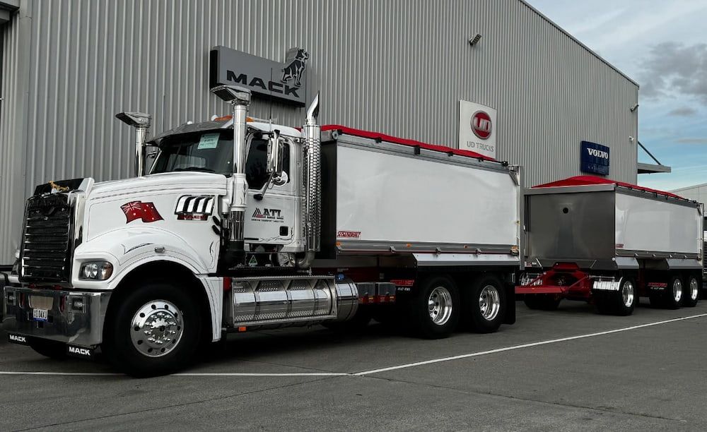 A White Dump Truck Is Parked In Front Of A Building — Armour Transport Logistics In Rutherford, NSW