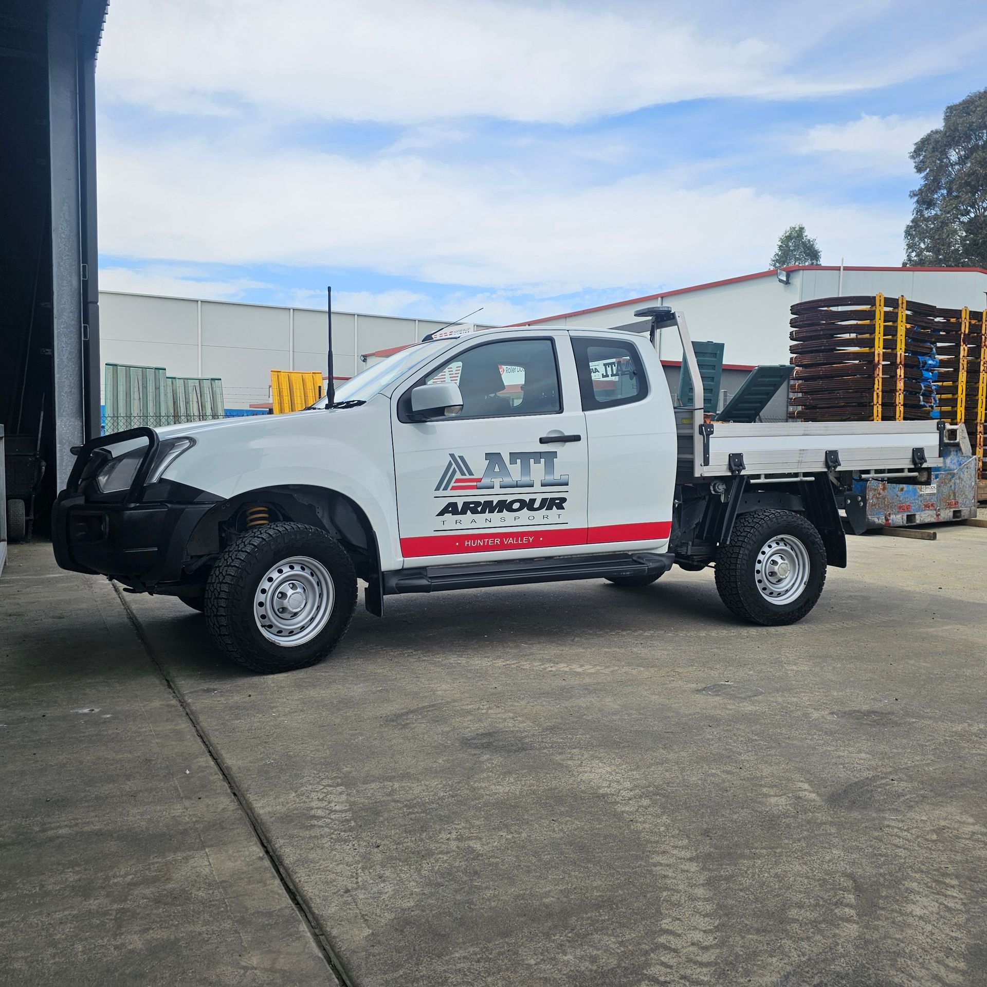 A white truck is parked in a parking lot in front of a building. Armour Transport Logistics In Rutherford, NSW