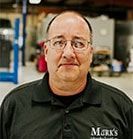 Man wearing glasses and a black shirt with logo 