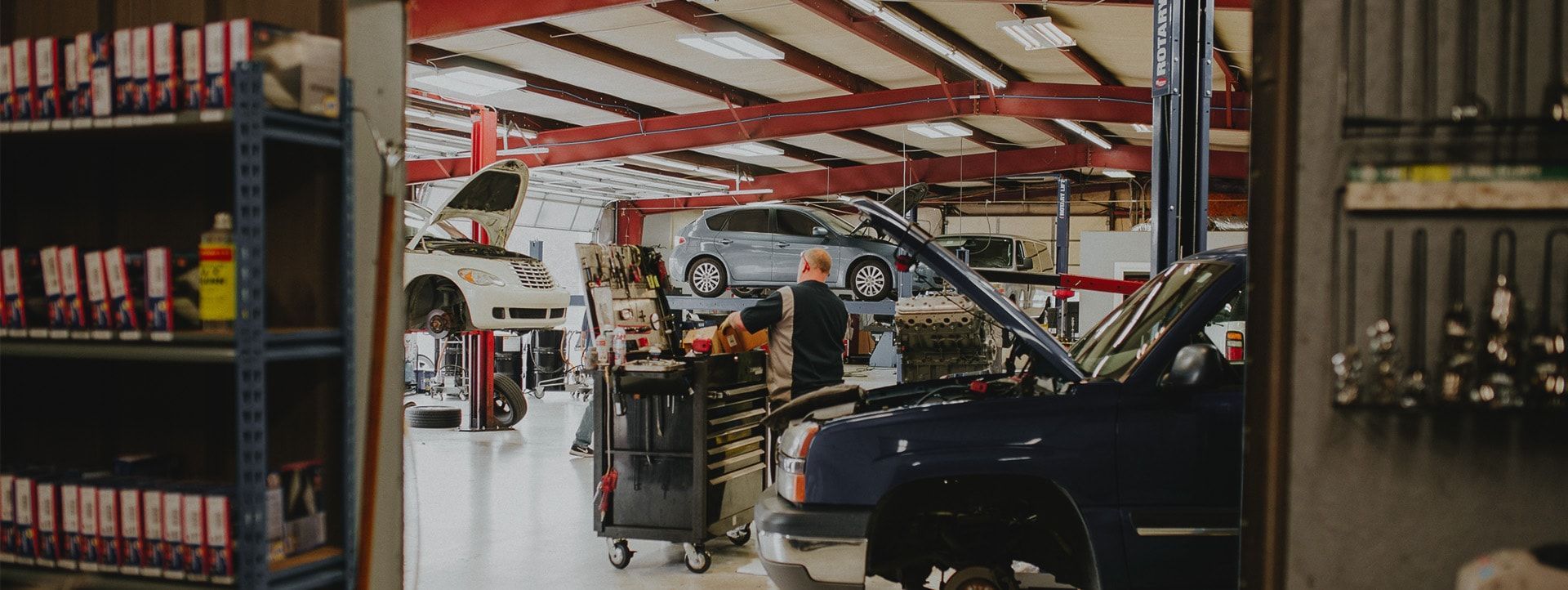 A car repair shop. A mechanic with a toolbox stands near a car. Other cars are on lifts. | Emge's Car Craft Auto Services
