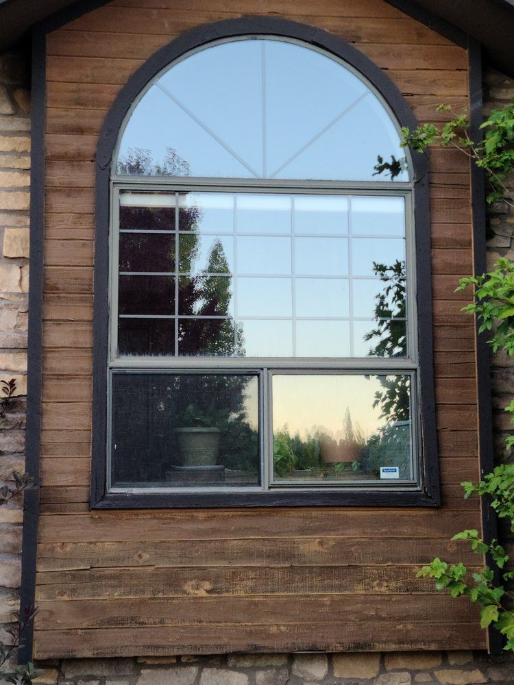 A large arched window on a wooden house