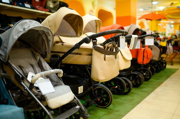 Una fila di passeggini beige e neri esposti in una corsia di un negozio.