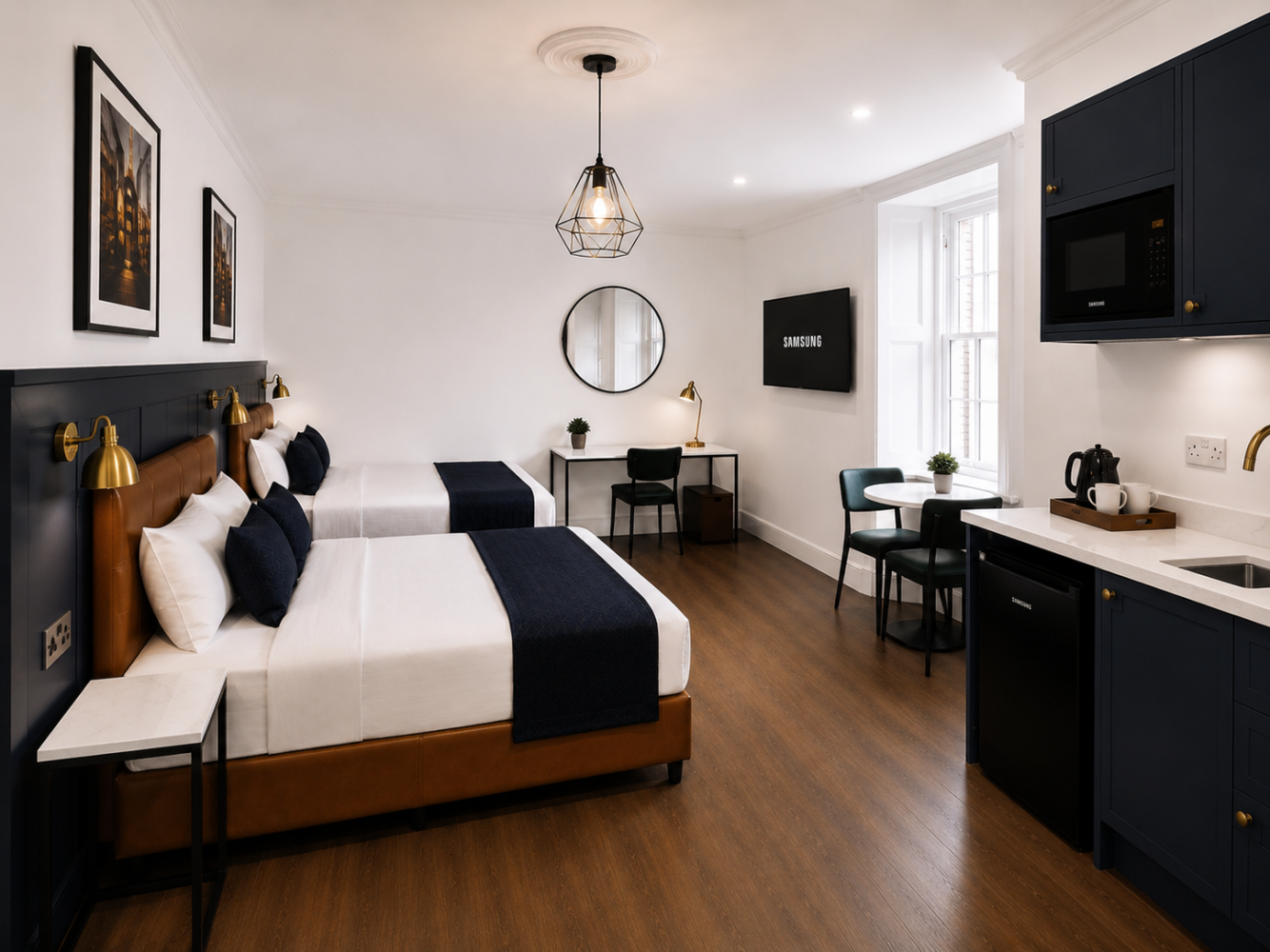 Modern studio bedroom with bed, desk, kitchenette, and wall-mounted TV in a bright, minimalist space
