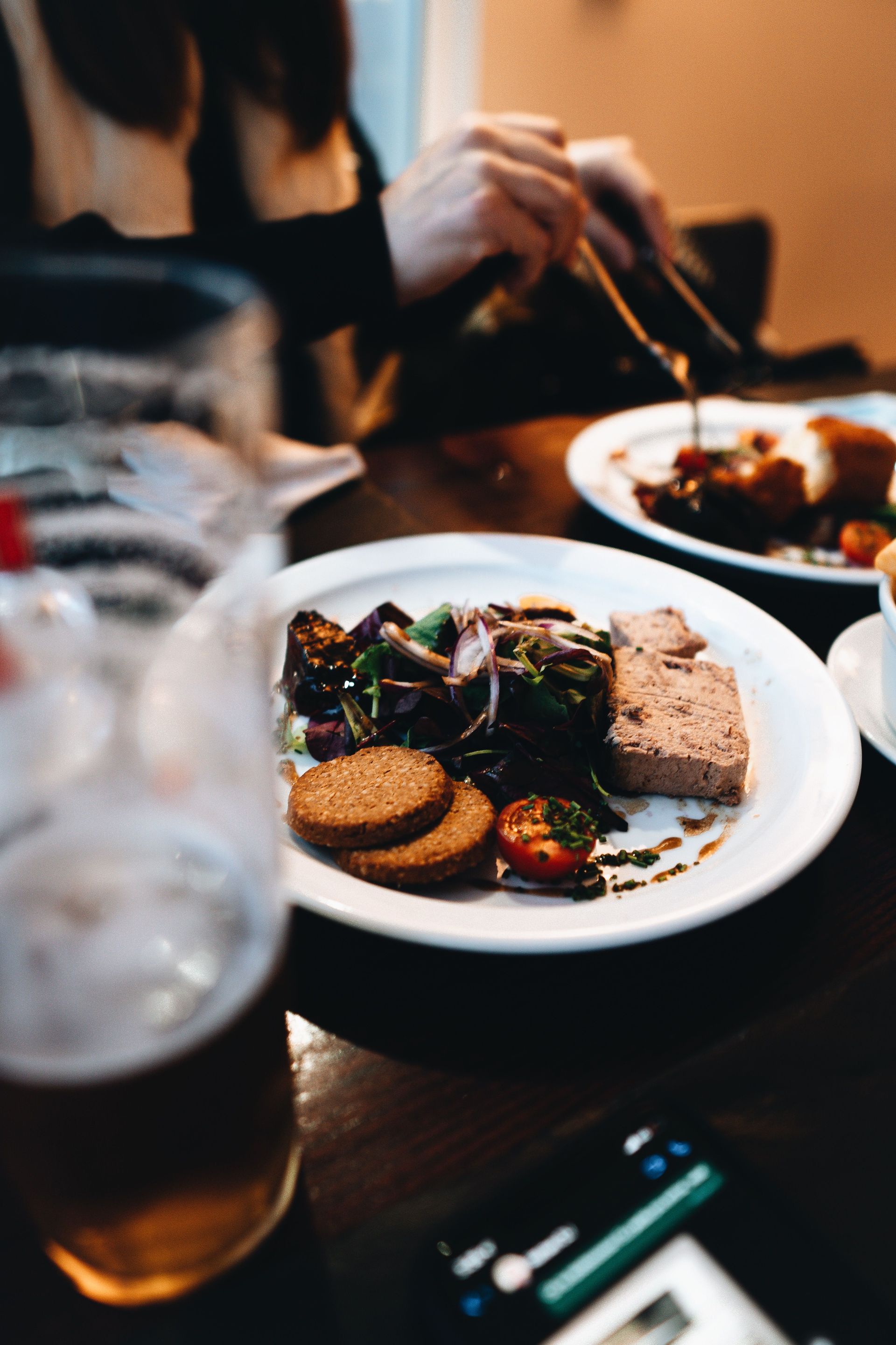 Dining table with plated dessert and drinks, while someone reaches with chopsticks in the background
