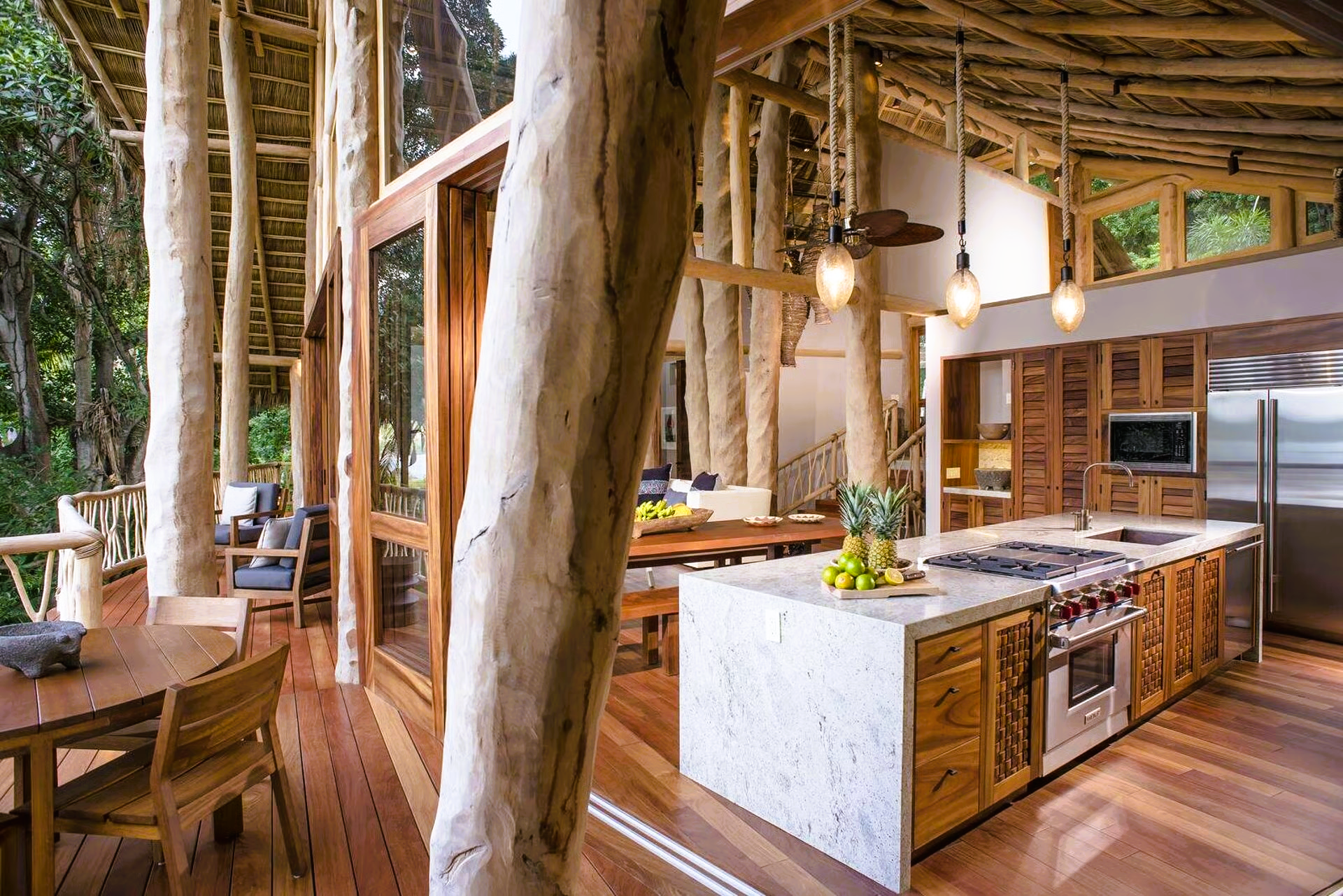 Wooden kitchen with island, Wolf range, and dining area, inside a treehouse-style building.