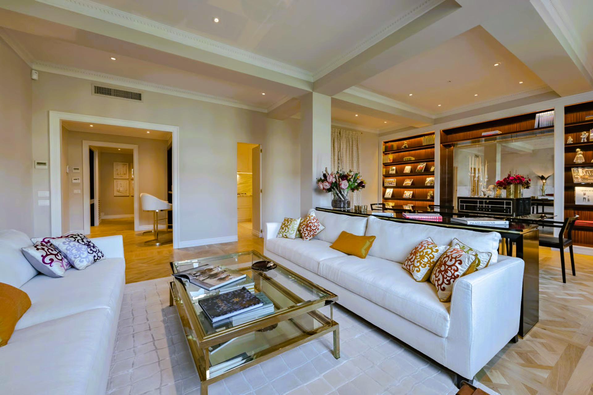 Spacious living room with white sofas, gold coffee table, dining area with a long table.