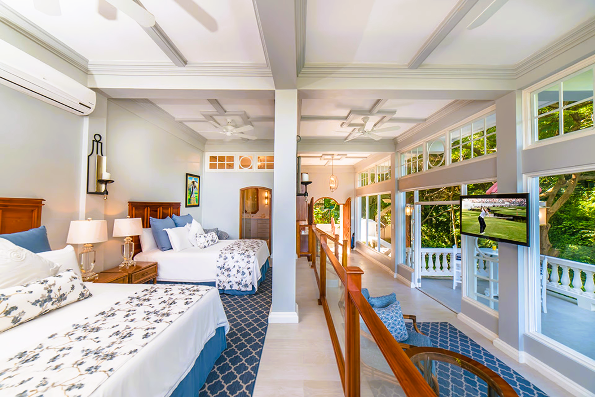 Spacious bedroom with two beds, balcony, and TV, featuring light blue and white decor.