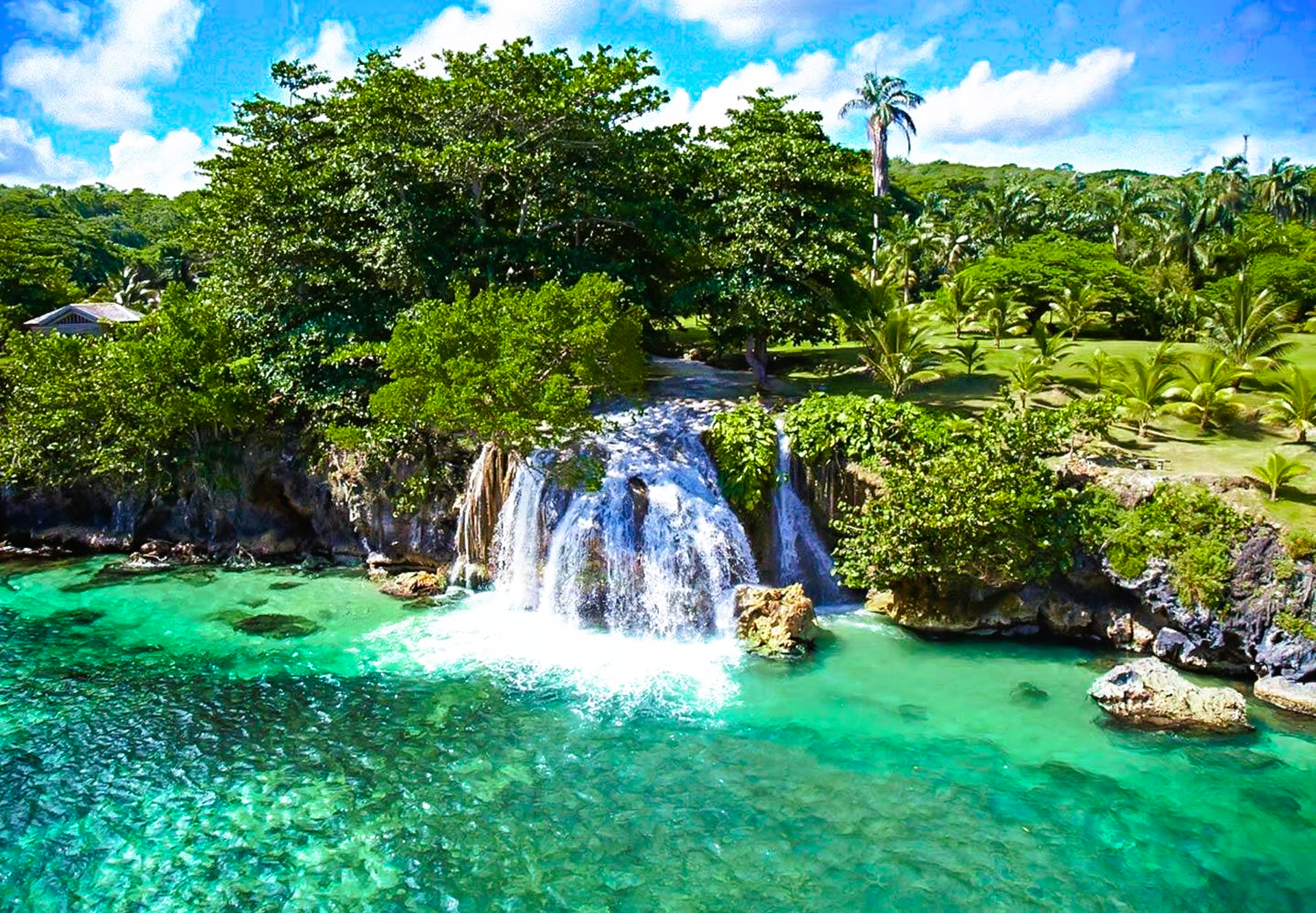 Waterfall cascading into turquoise water, surrounded by lush green vegetation.