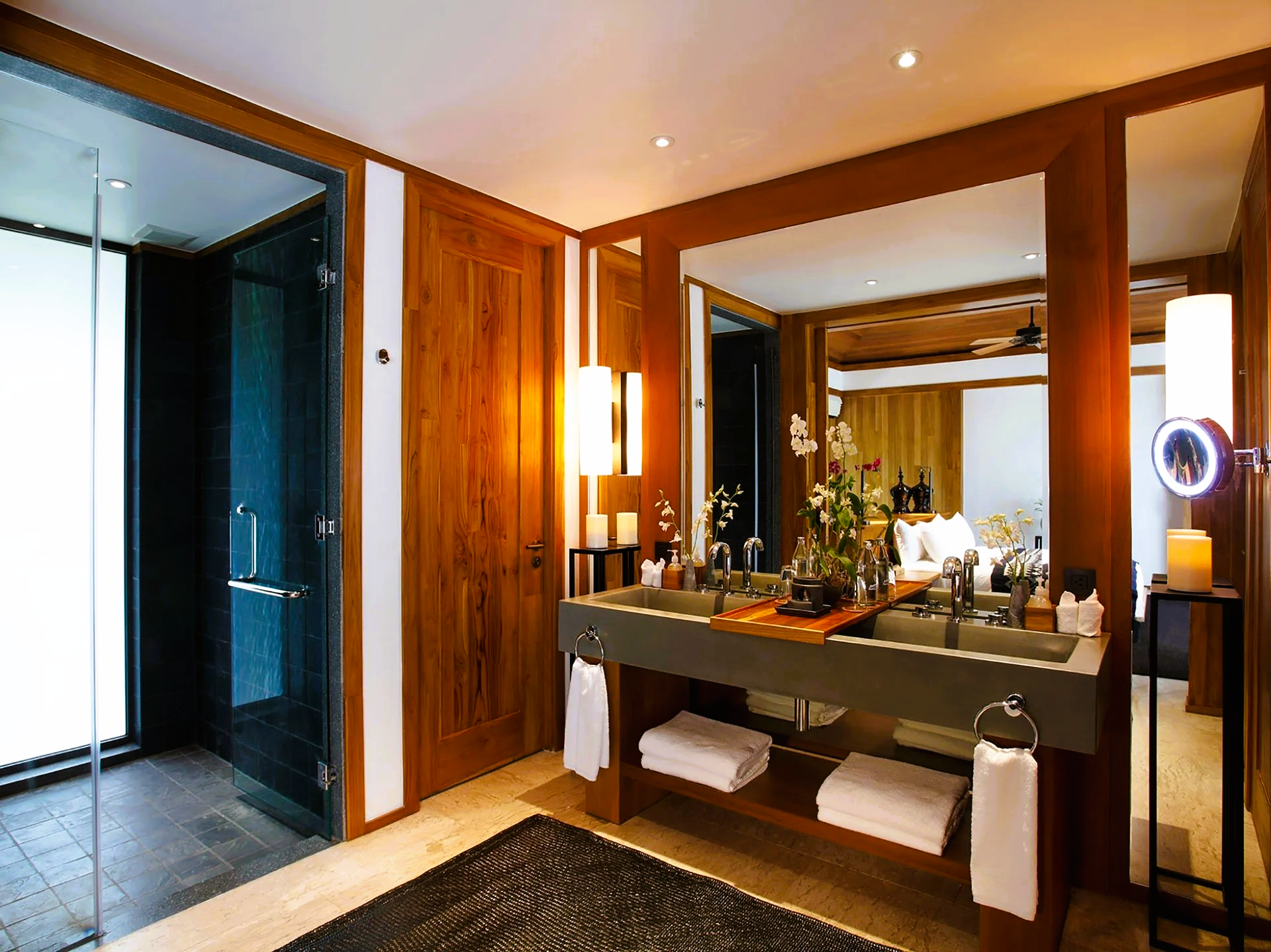 Luxurious bathroom with wood paneling, a large mirror, double sinks, and a glass shower.