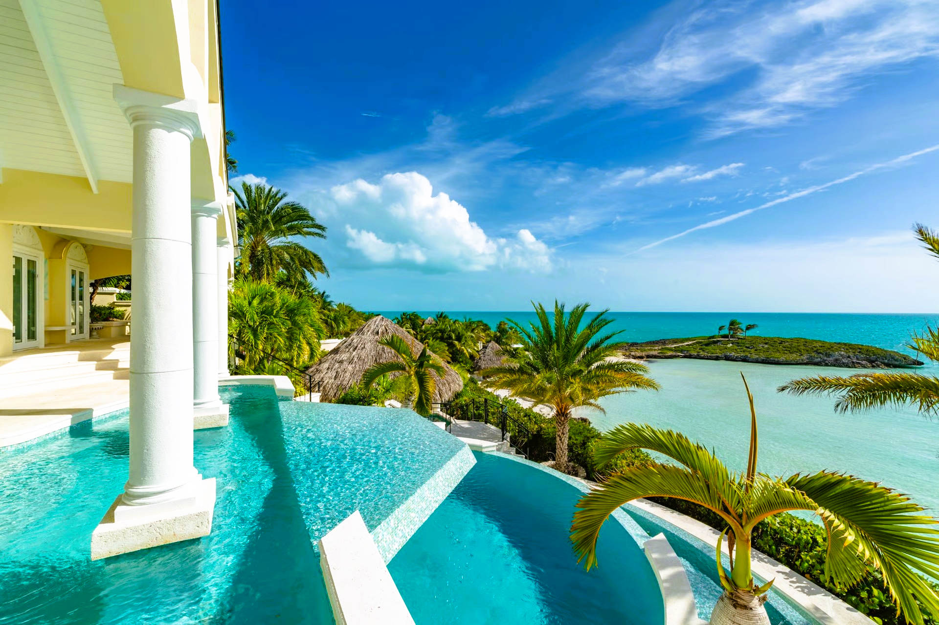Luxury villa with turquoise infinity pool overlooking a tropical ocean view.