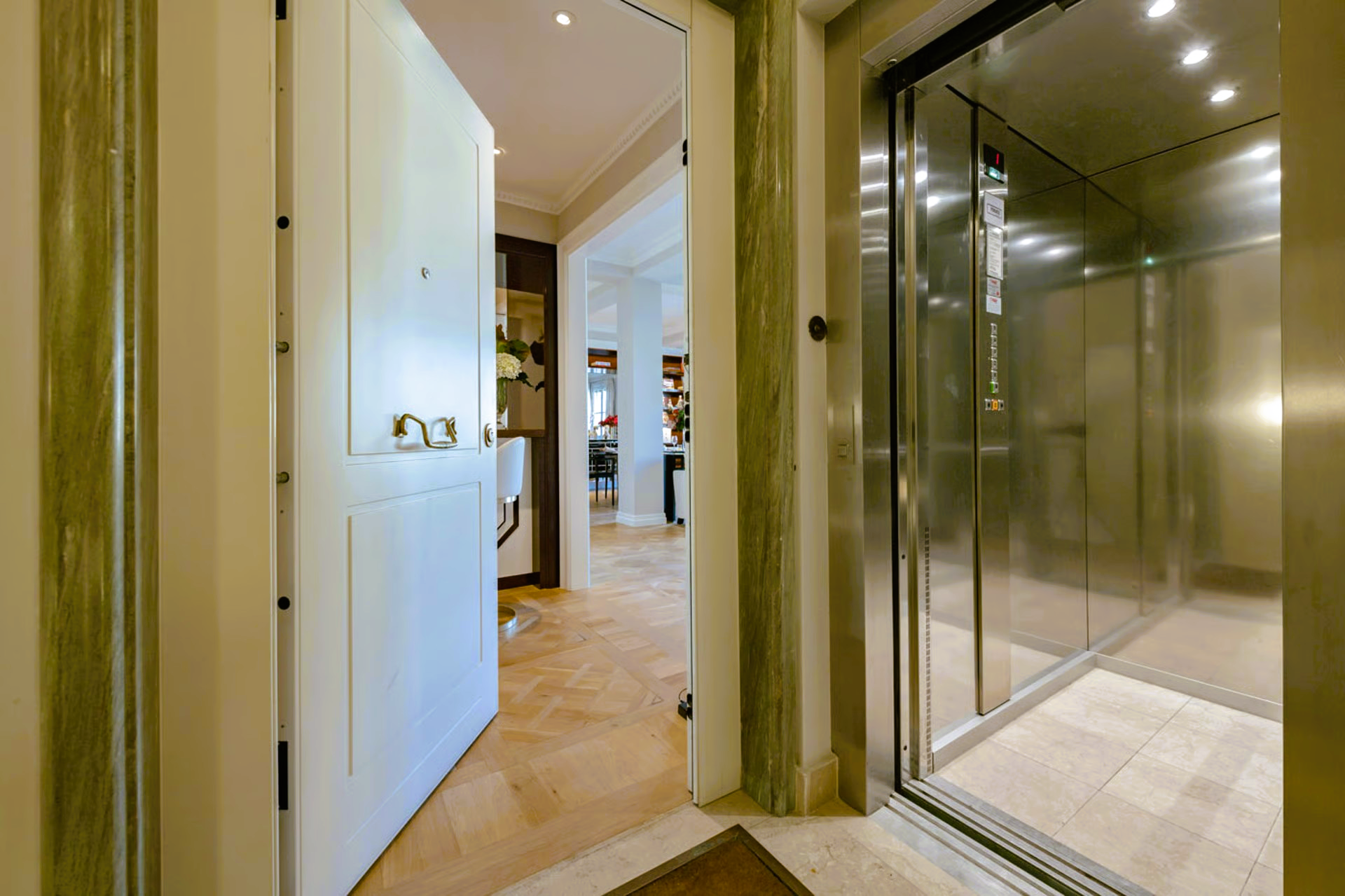 Open white door reveals hallway; elevator on right.