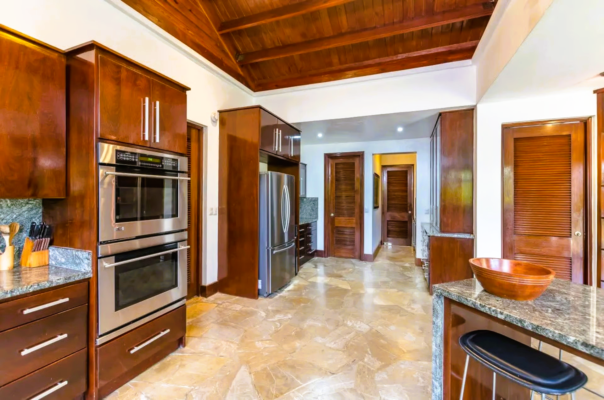 Kitchen with wood cabinets, stainless steel appliances, granite countertops, and tile floor.