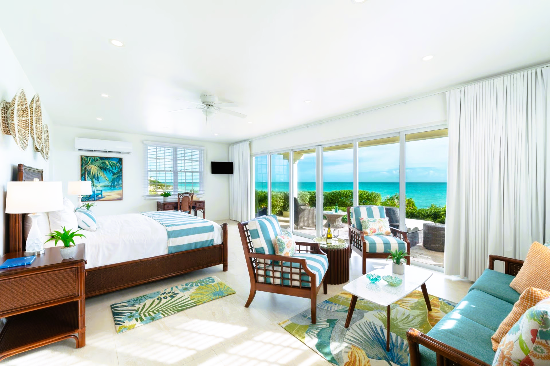 Bright beachfront suite with ocean view, teal and brown furnishings, patio access.
