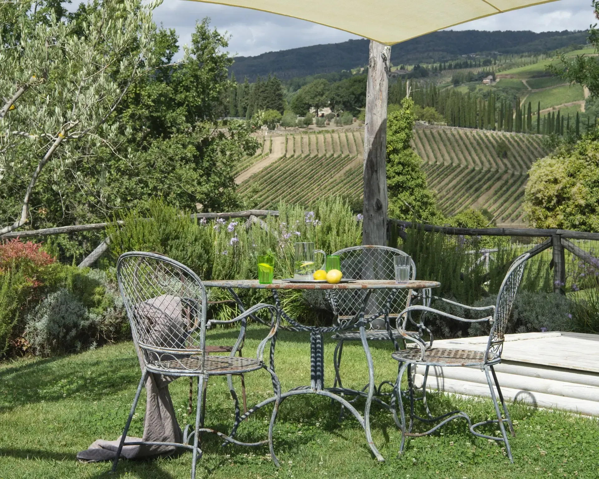 Outdoor patio with metal furniture, overlooking a vineyard in Tuscany.