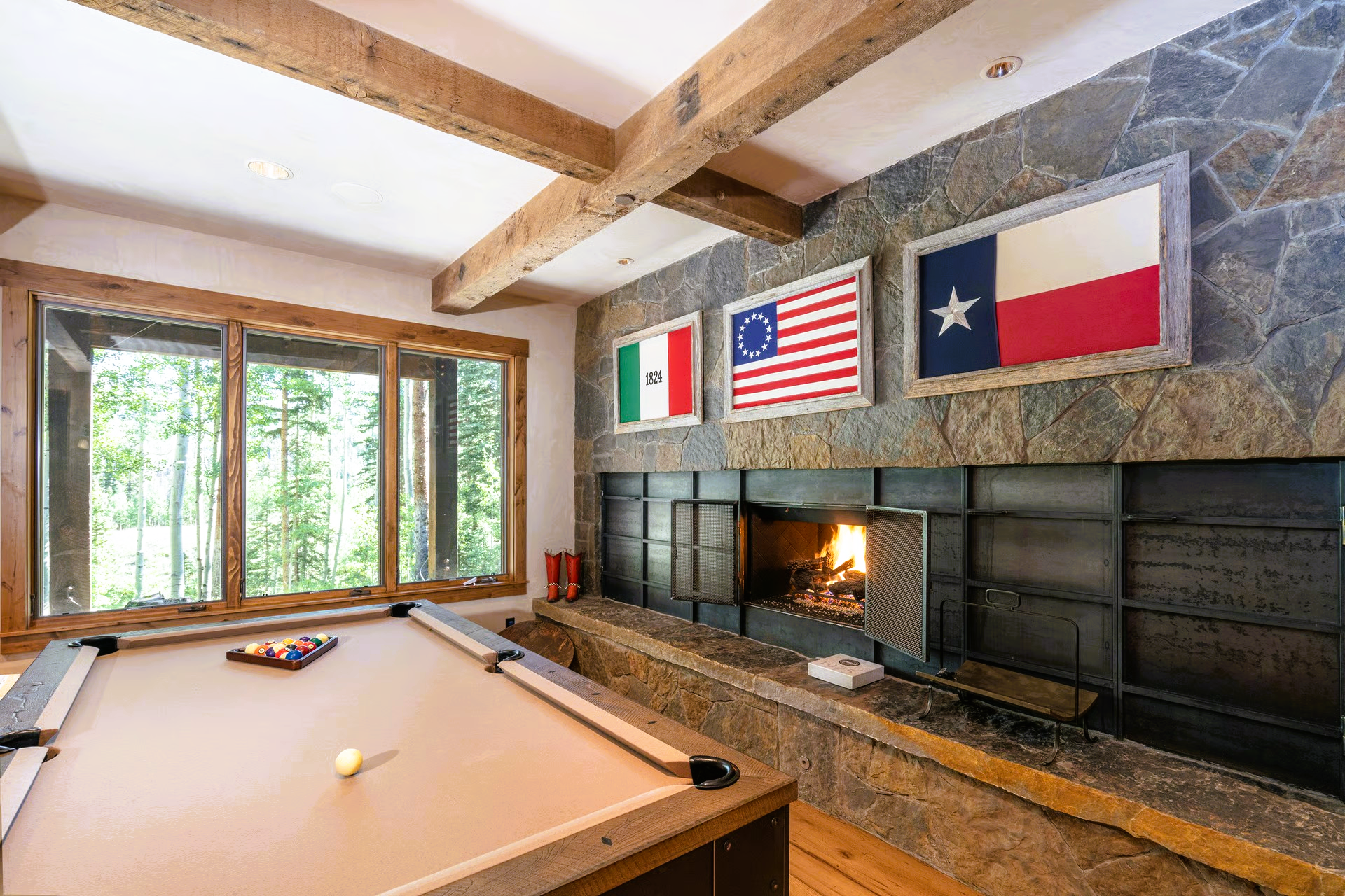 Pool table in a room with a fireplace and flags of Italy, U.S., and Texas.