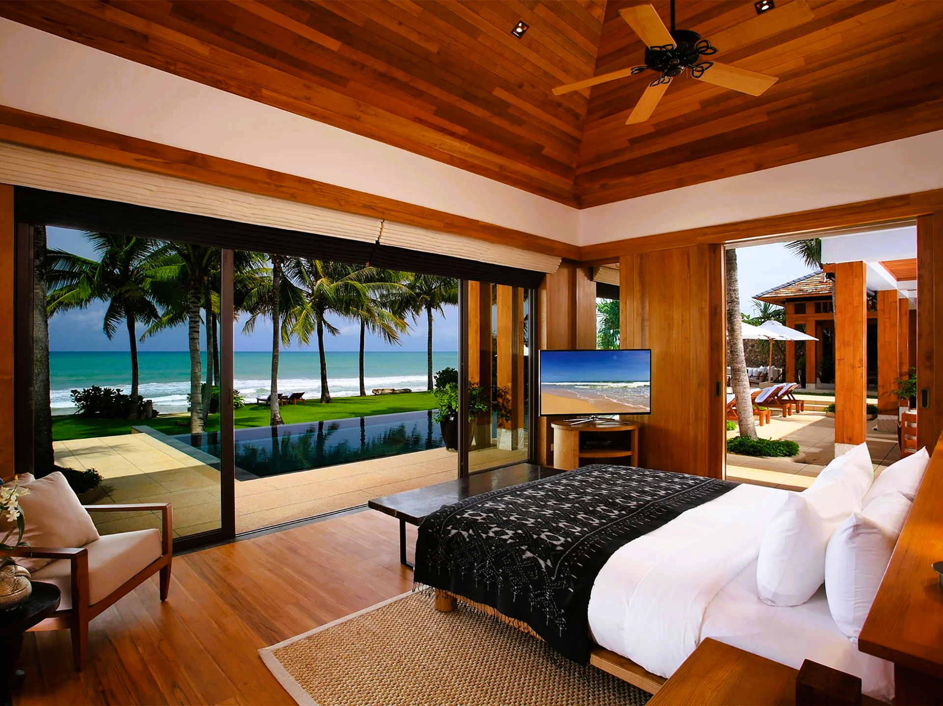 Bedroom with a king-sized bed, sliding glass doors to a pool and ocean view, wooden ceiling and walls.