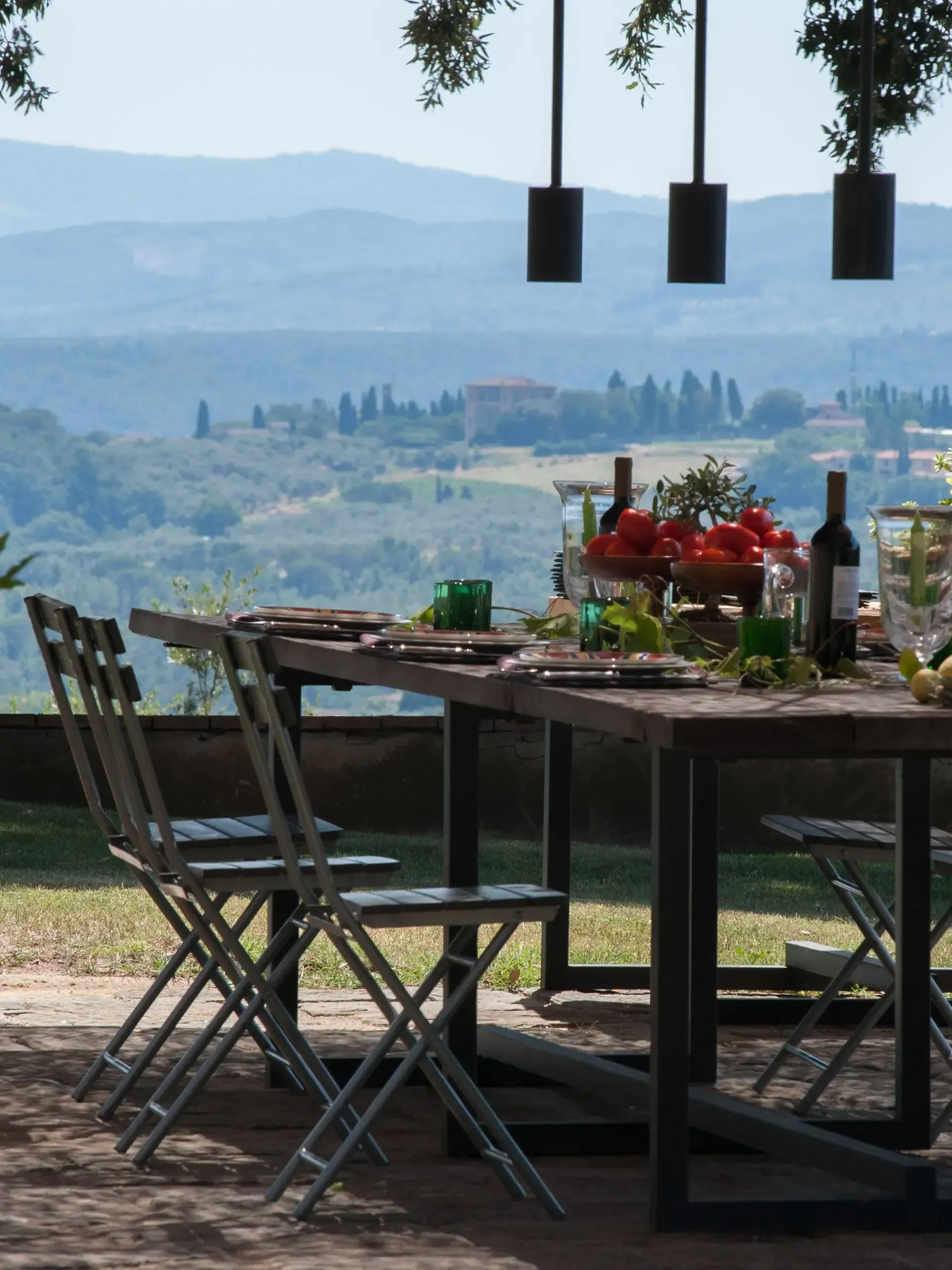 Outdoor dining table set for a meal, with a scenic hilltop view.