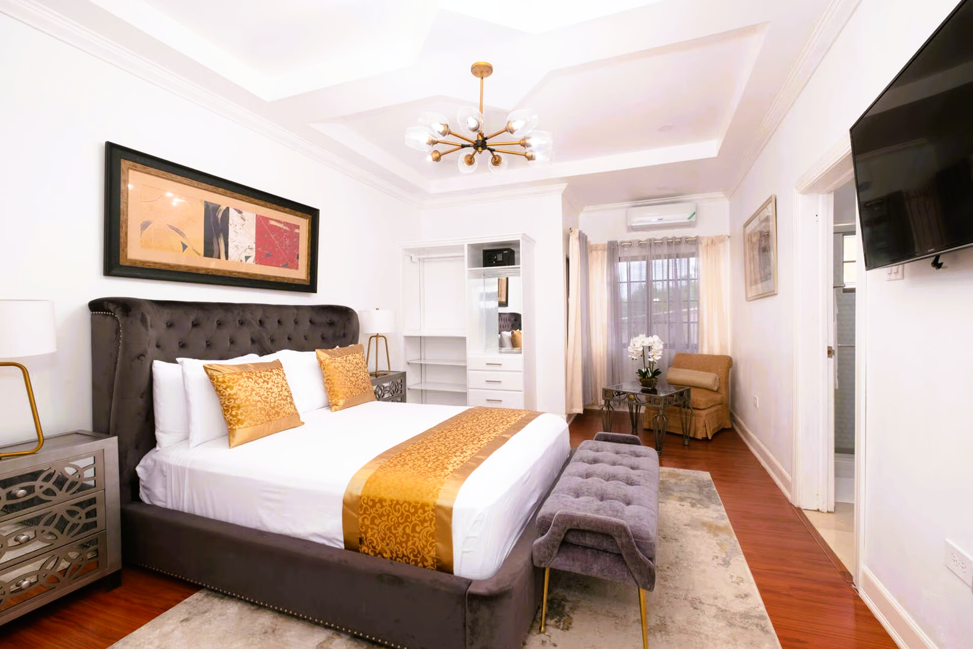 Luxurious bedroom with a large bed, gold accents, and a TV on the wall.