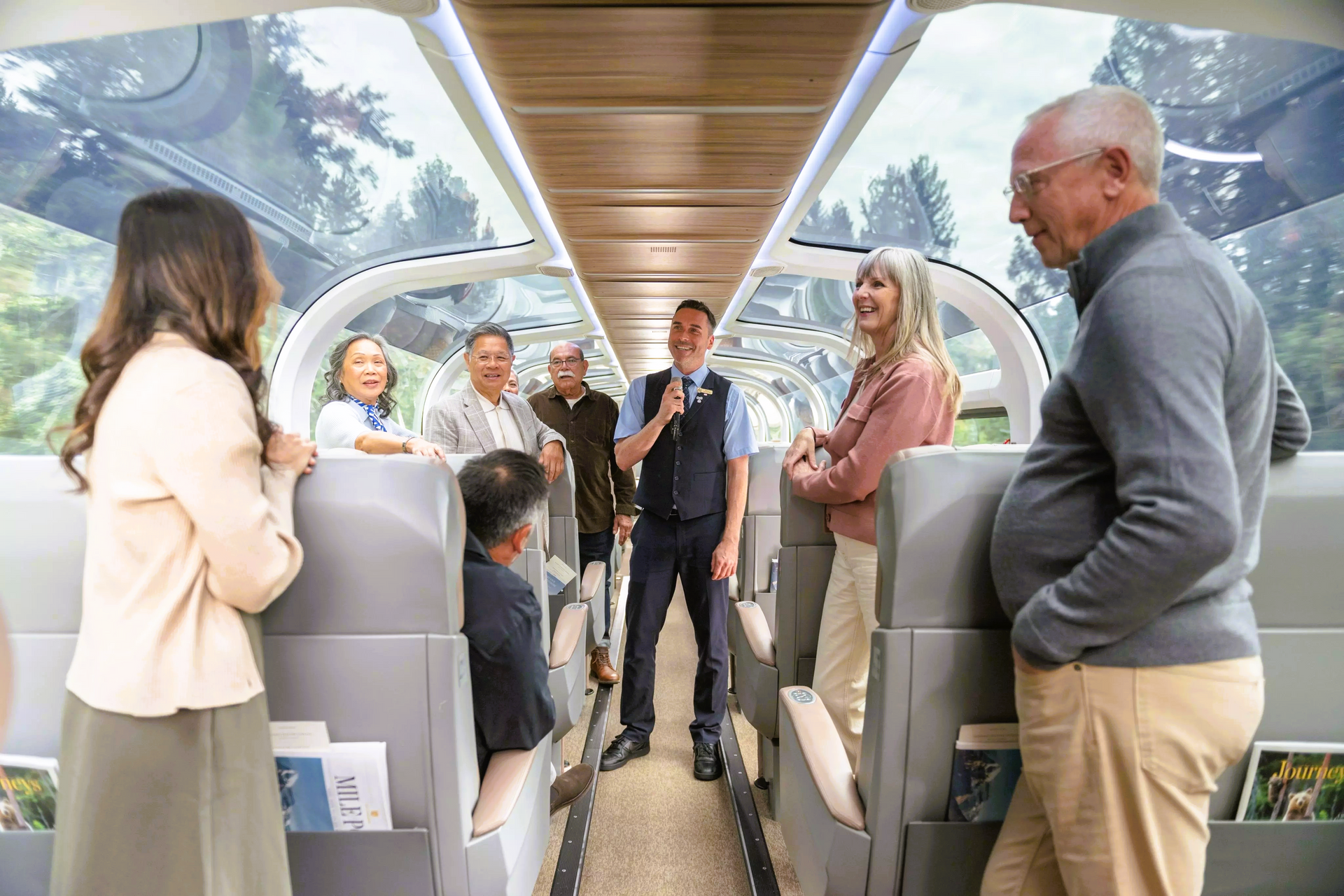 People inside a train car with a guide, enjoying the view from a glass roof.