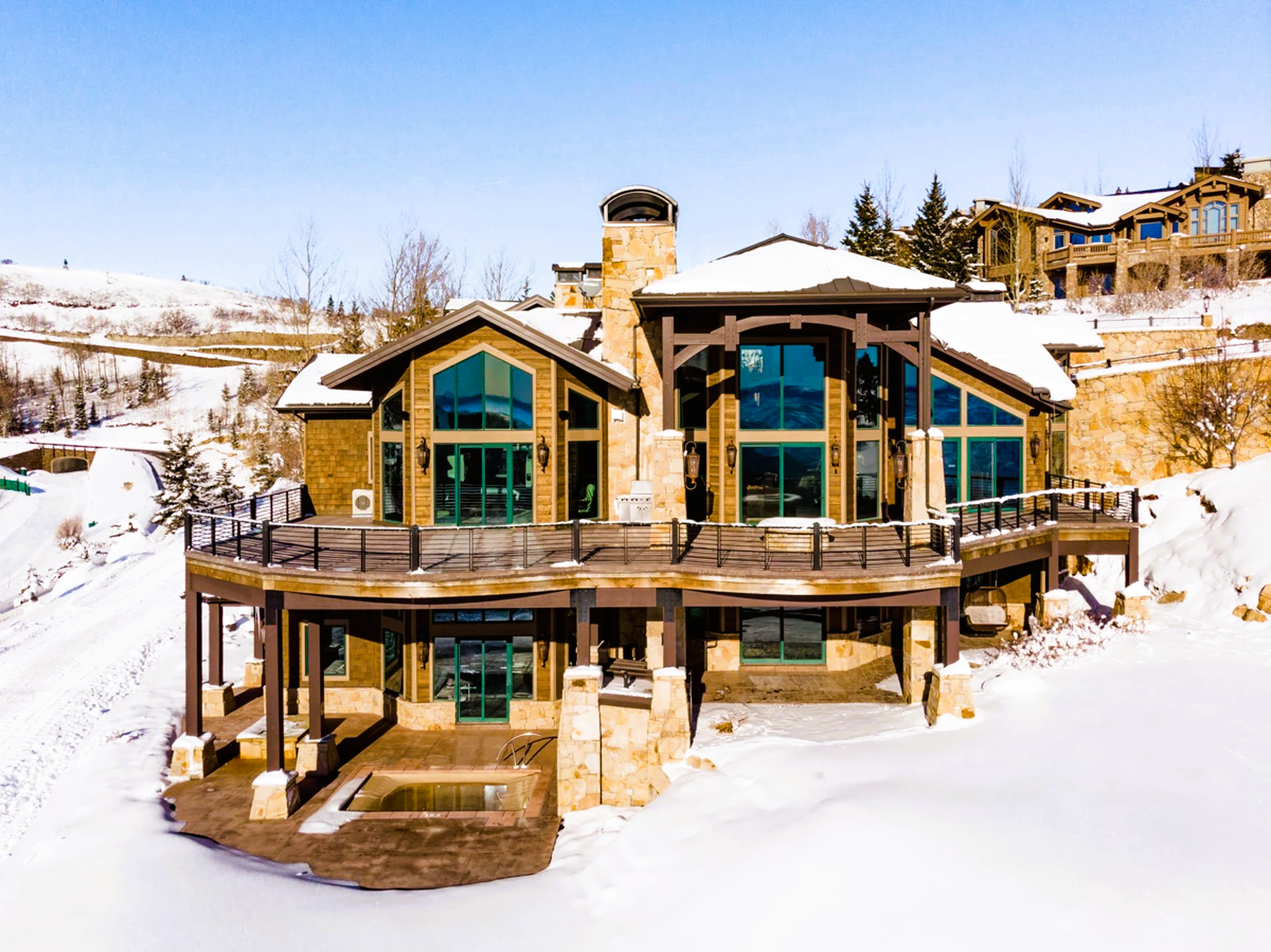 Mountain home with large windows and wooden accents, surrounded by snow.