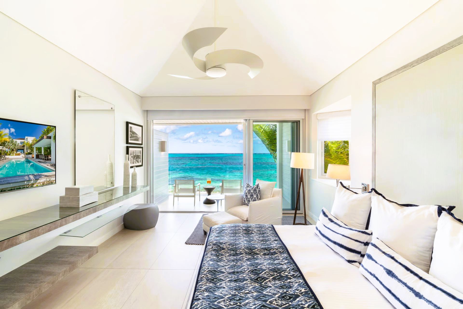 Bright, airy bedroom with ocean view, featuring a king bed, lounge chair, and sliding doors.