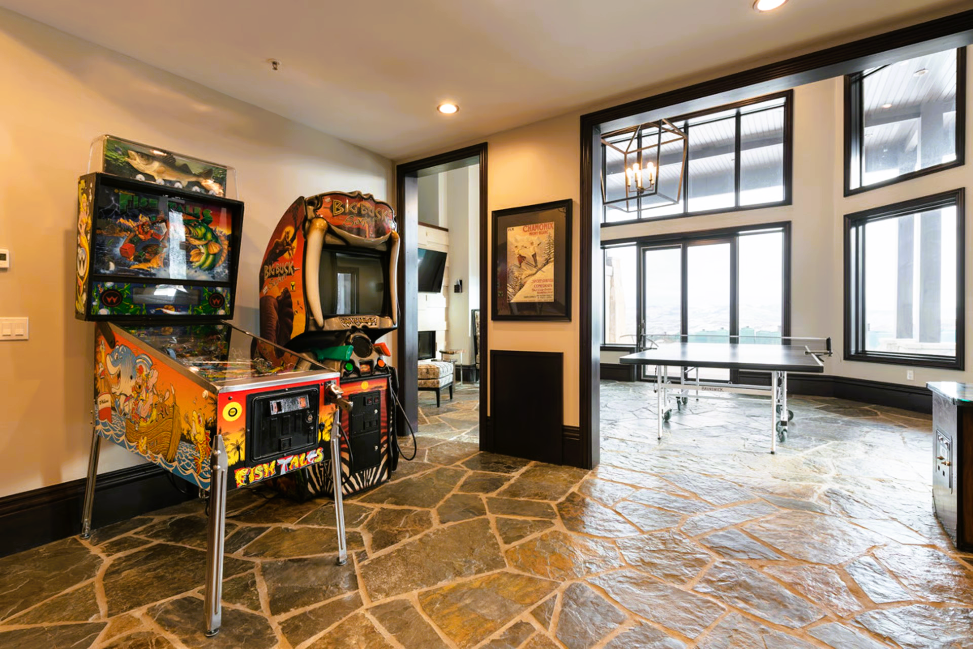 Game room with pinball machines, view of dining area, and stone flooring.